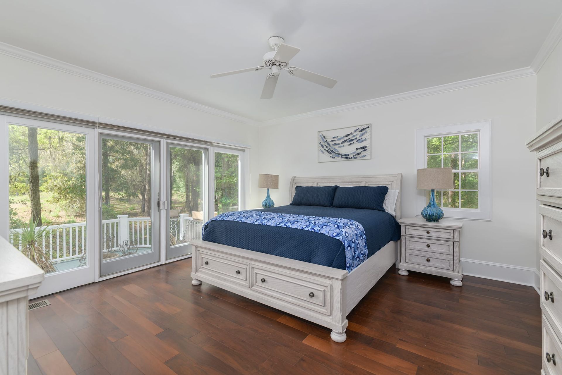 A bedroom with a bed , dresser , nightstand , and sliding glass doors.