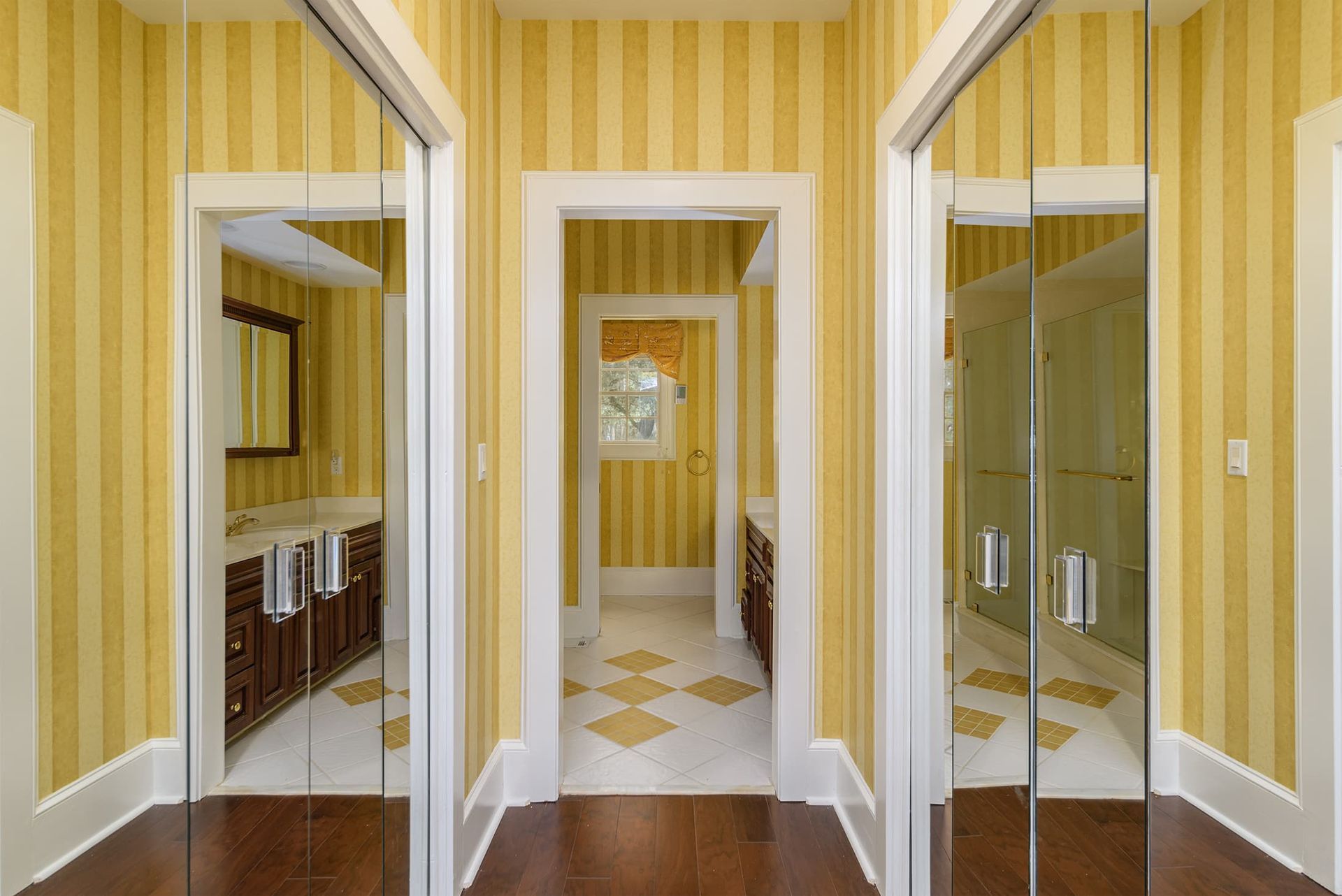 A hallway with yellow striped wallpaper and sliding glass doors leading to a bathroom.