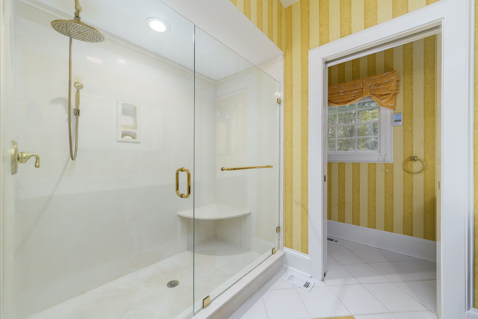A bathroom with a walk in shower with a glass door.