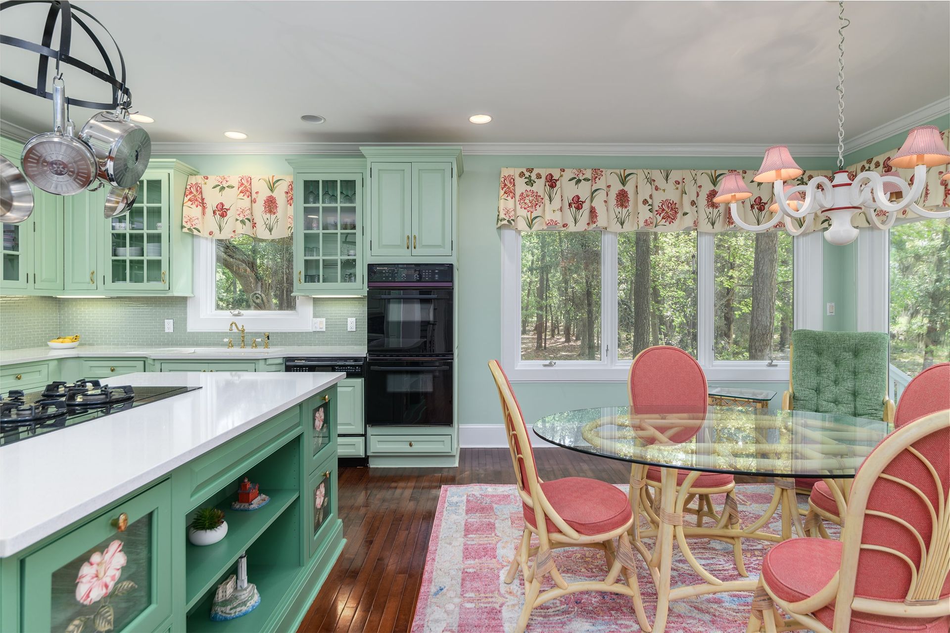 A kitchen with green cabinets and a glass table and chairs.
