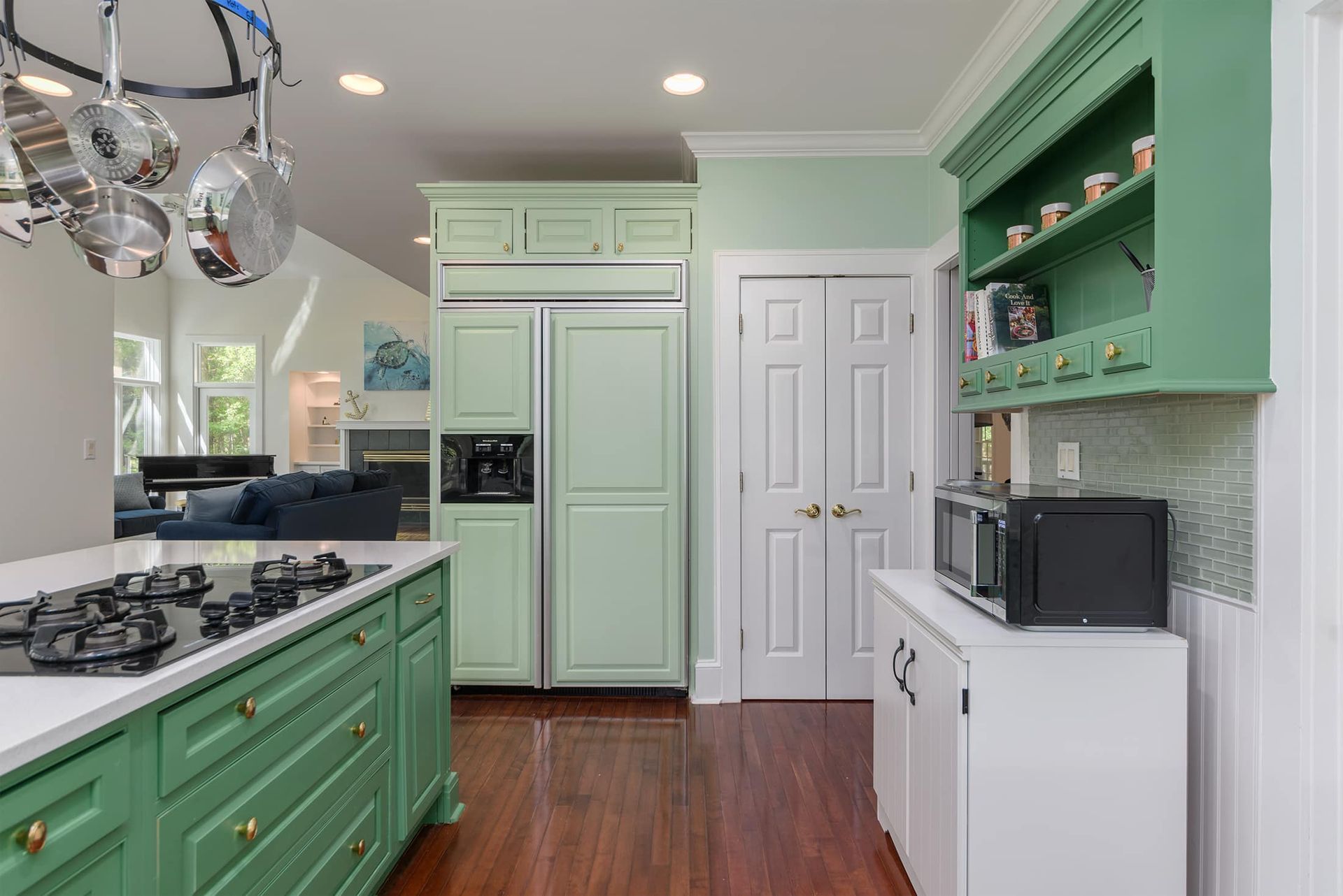 A kitchen with green cabinets , a stove top oven , a refrigerator and a microwave.