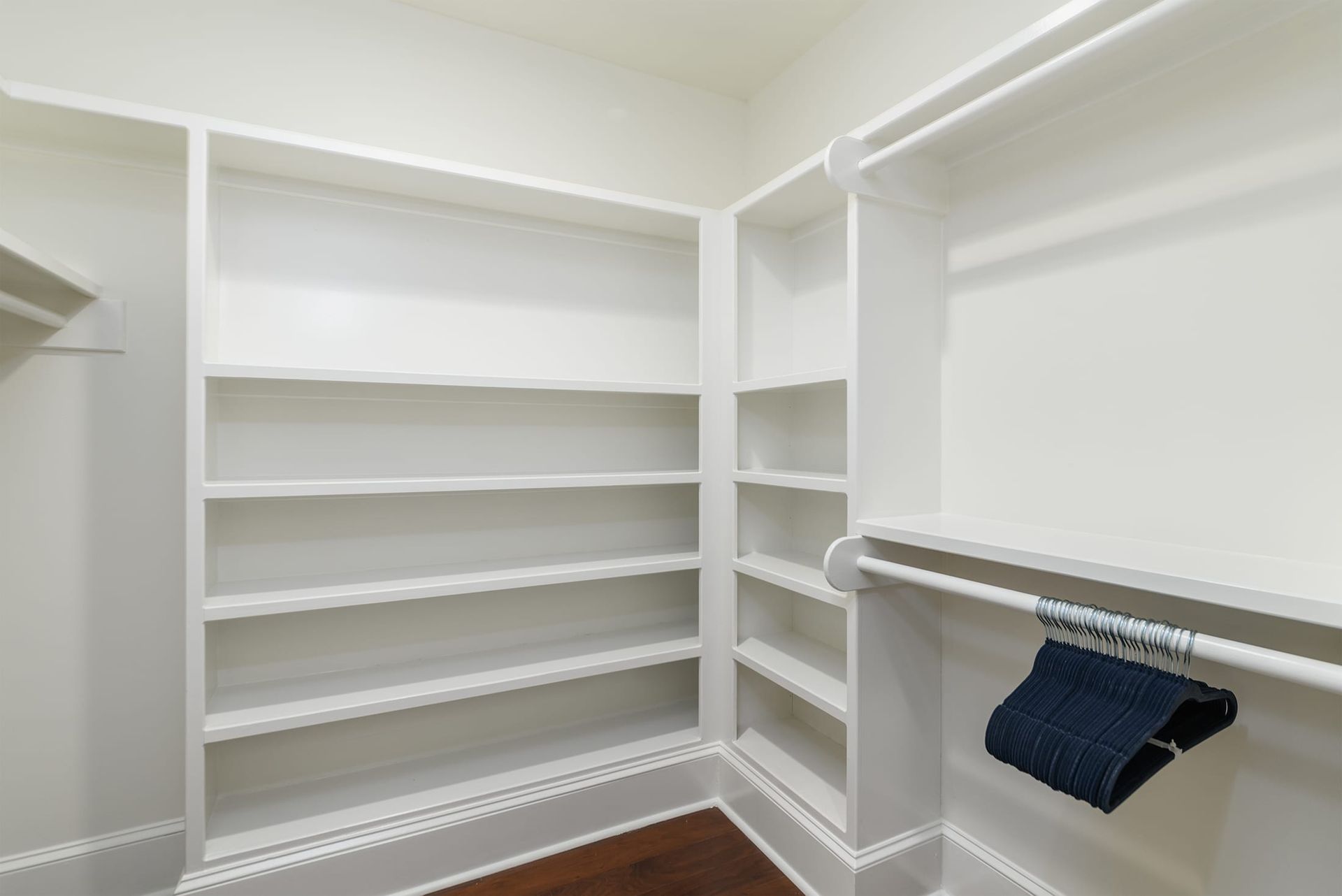 A walk in closet with lots of shelves and a hanger.