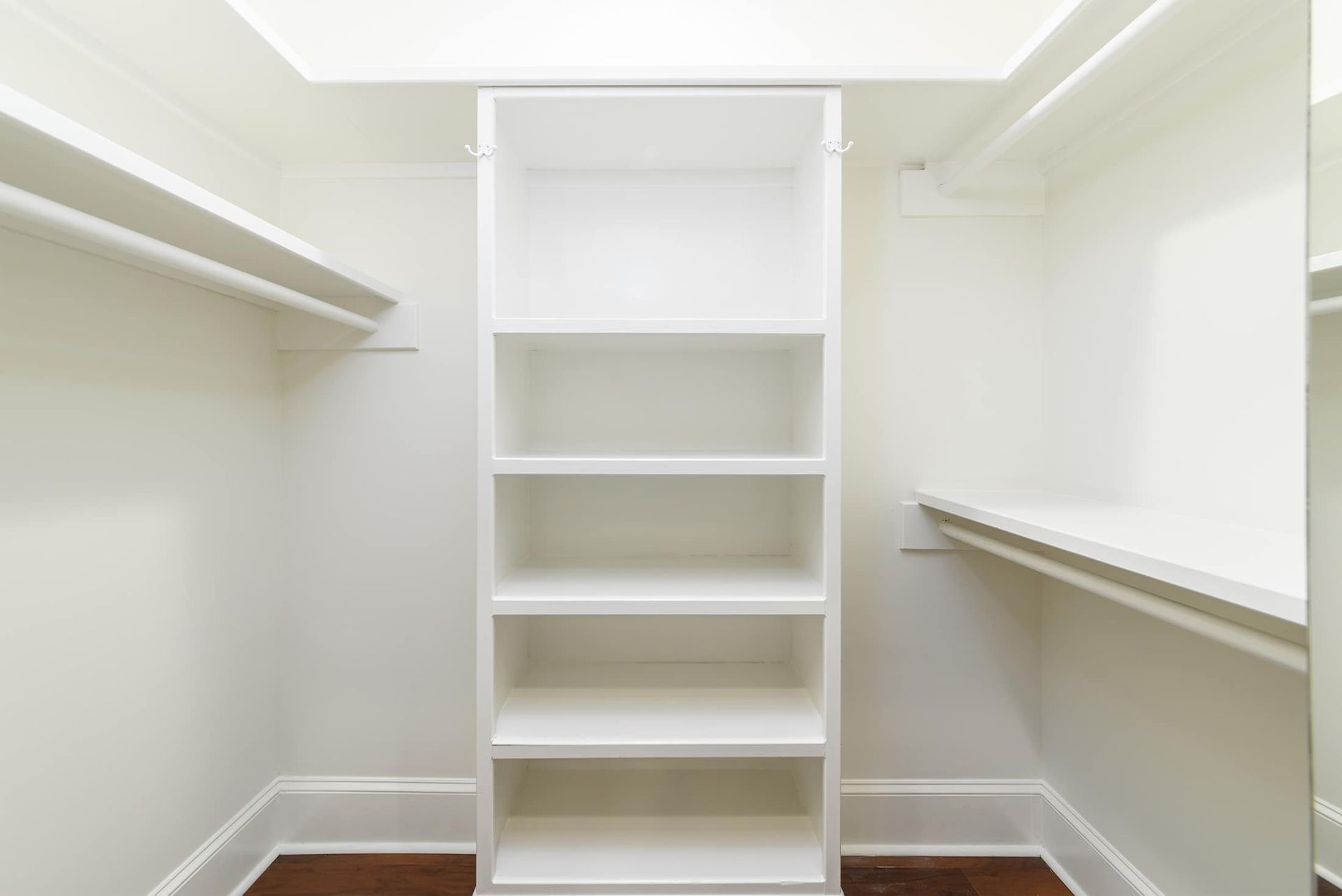 A walk in closet with white shelves and a mirror.