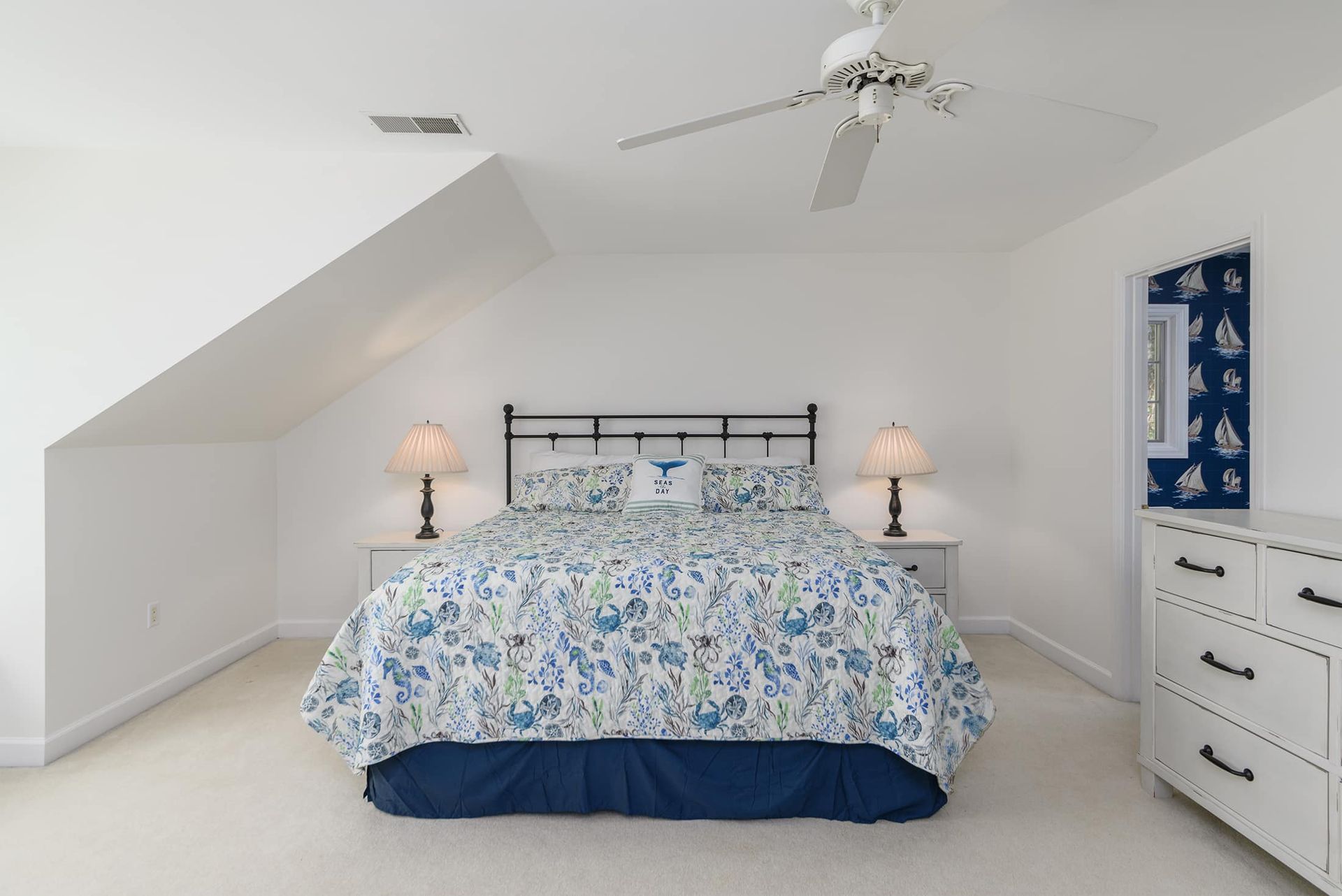 A bedroom with a king size bed and a ceiling fan.