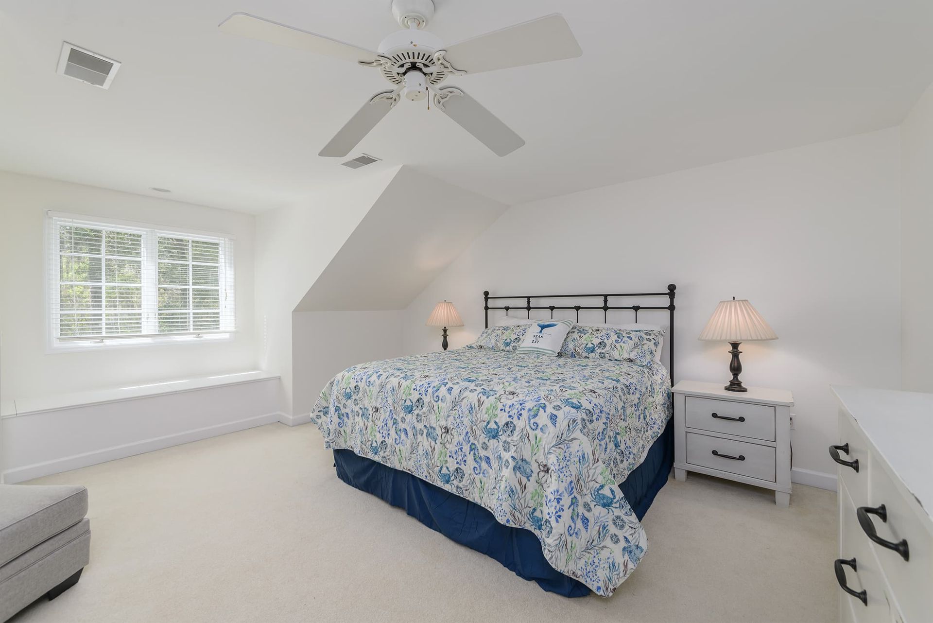 A bedroom with a bed , dresser , nightstand and ceiling fan.