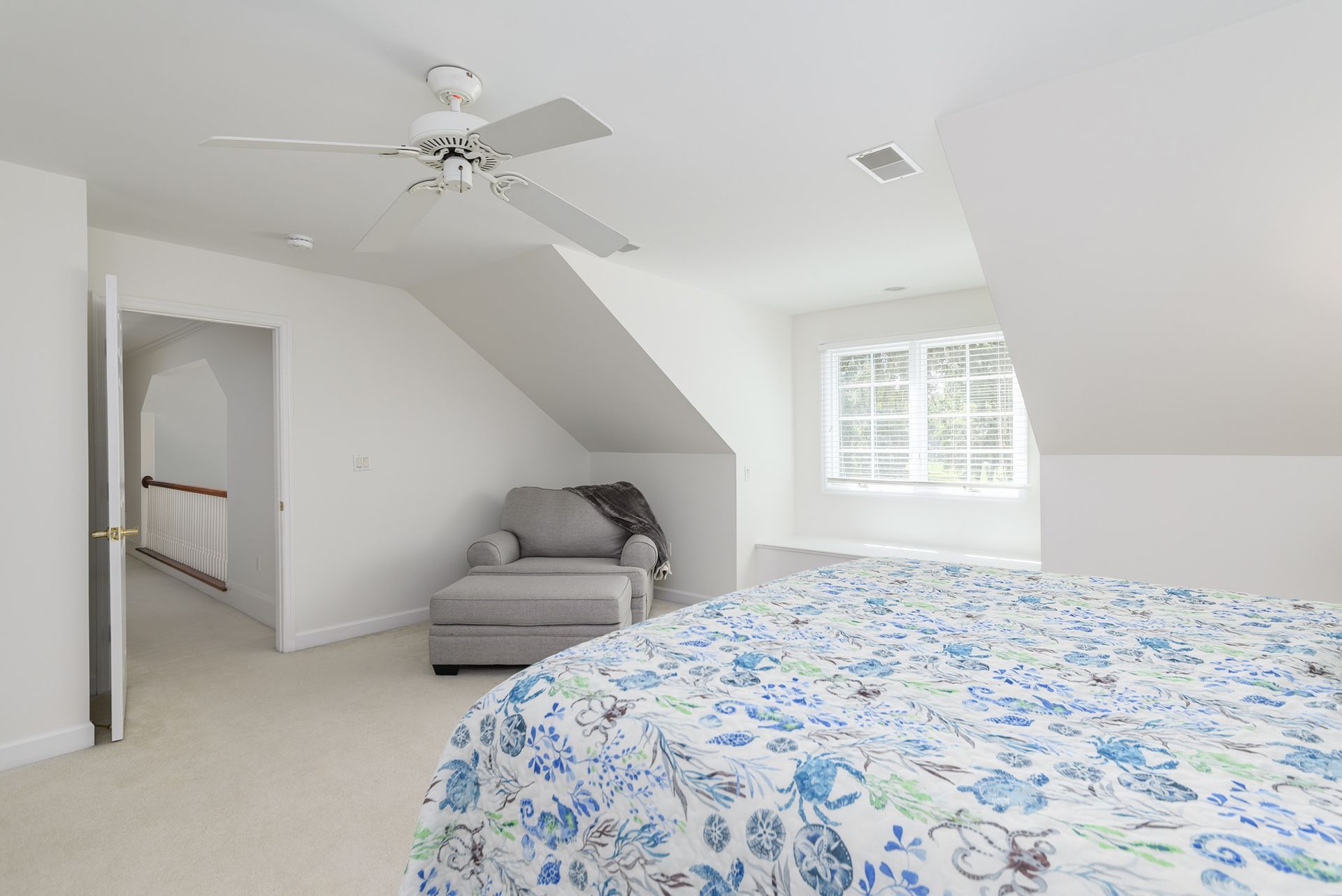 A bedroom with a bed , chair and ceiling fan.