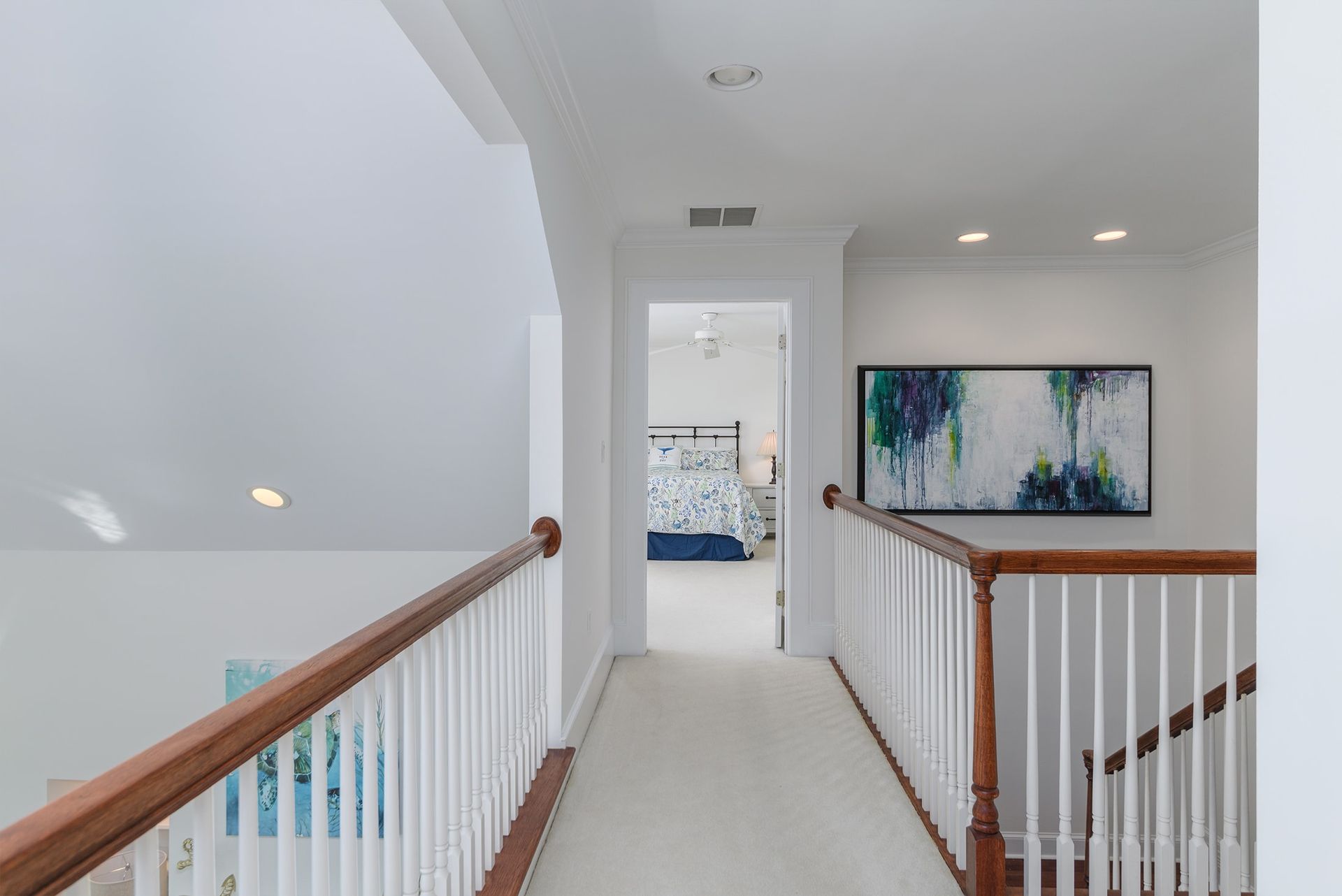 A hallway leading to a bedroom and a staircase in a house.