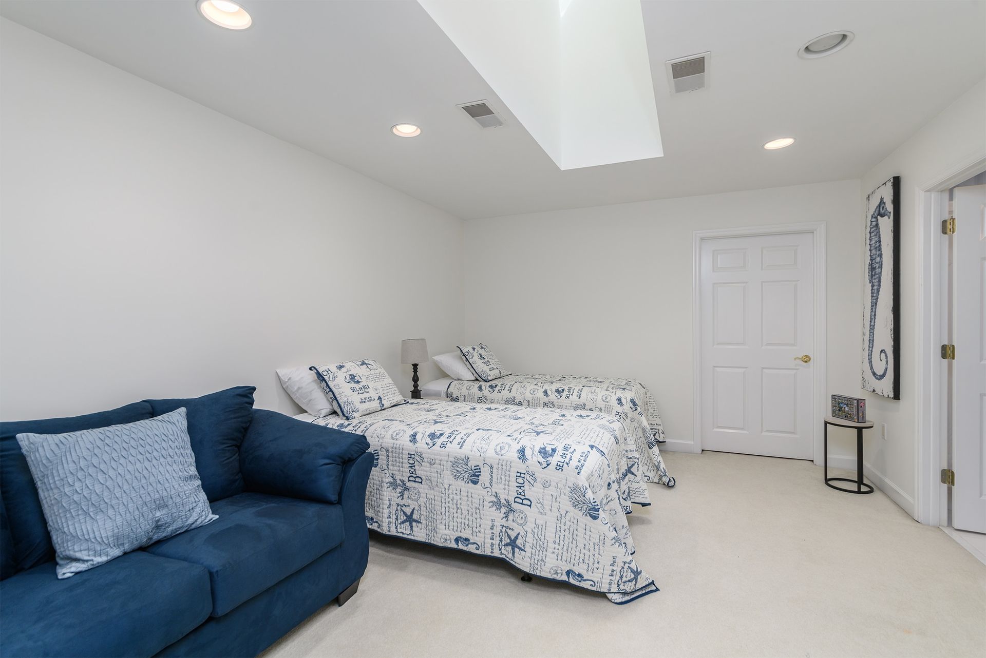 A bedroom with two beds and a blue couch