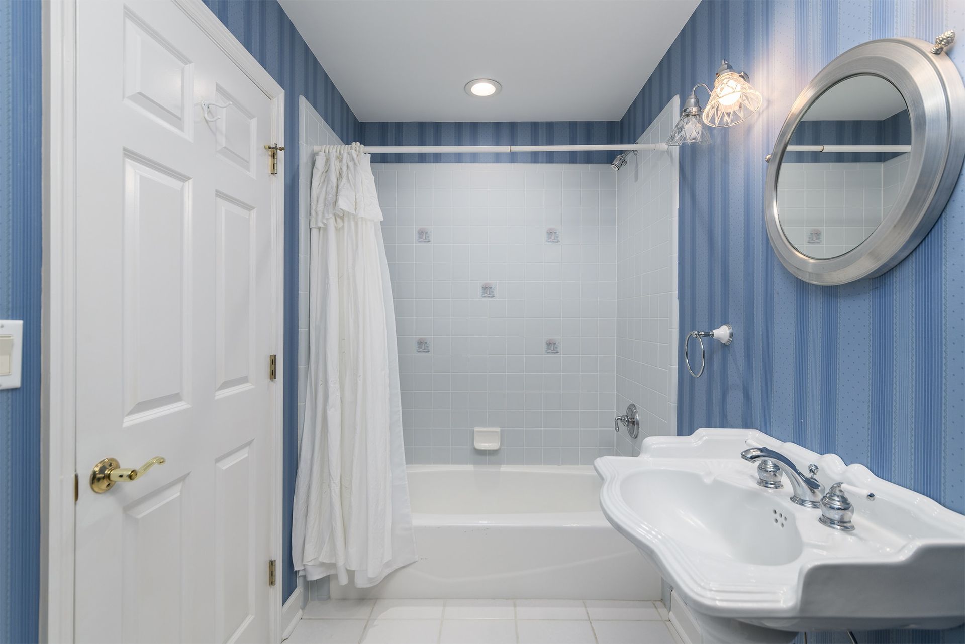A bathroom with blue walls , a sink , a tub , and a mirror.