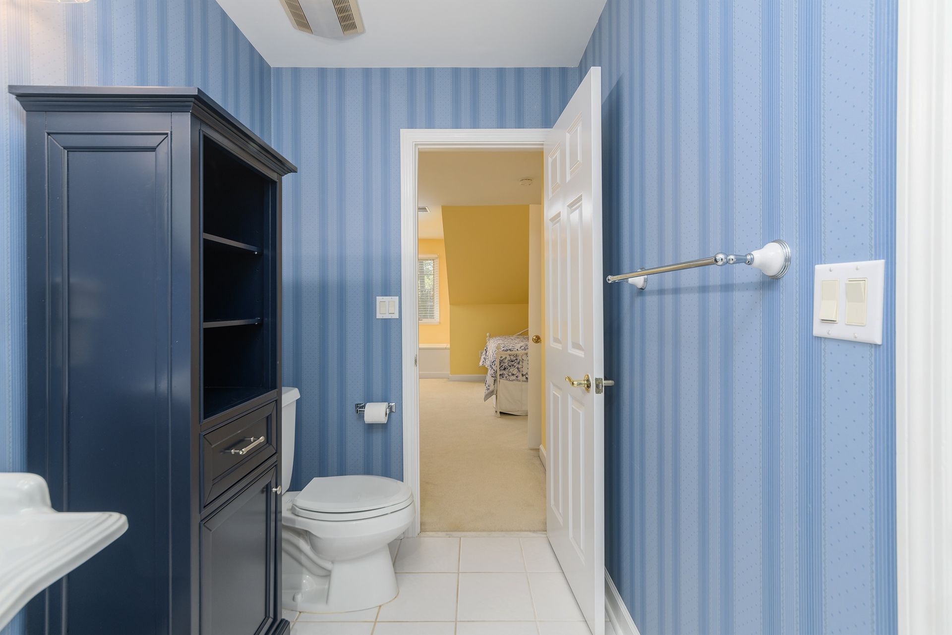 A bathroom with blue striped wallpaper and a toilet.