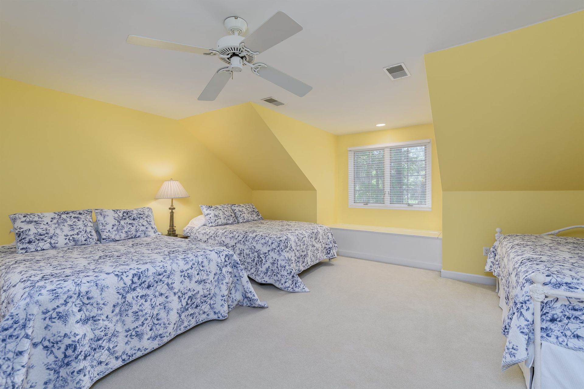 A bedroom with three beds and a ceiling fan