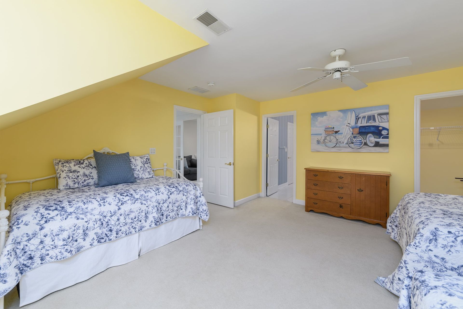 A bedroom with two beds , a dresser and a ceiling fan.