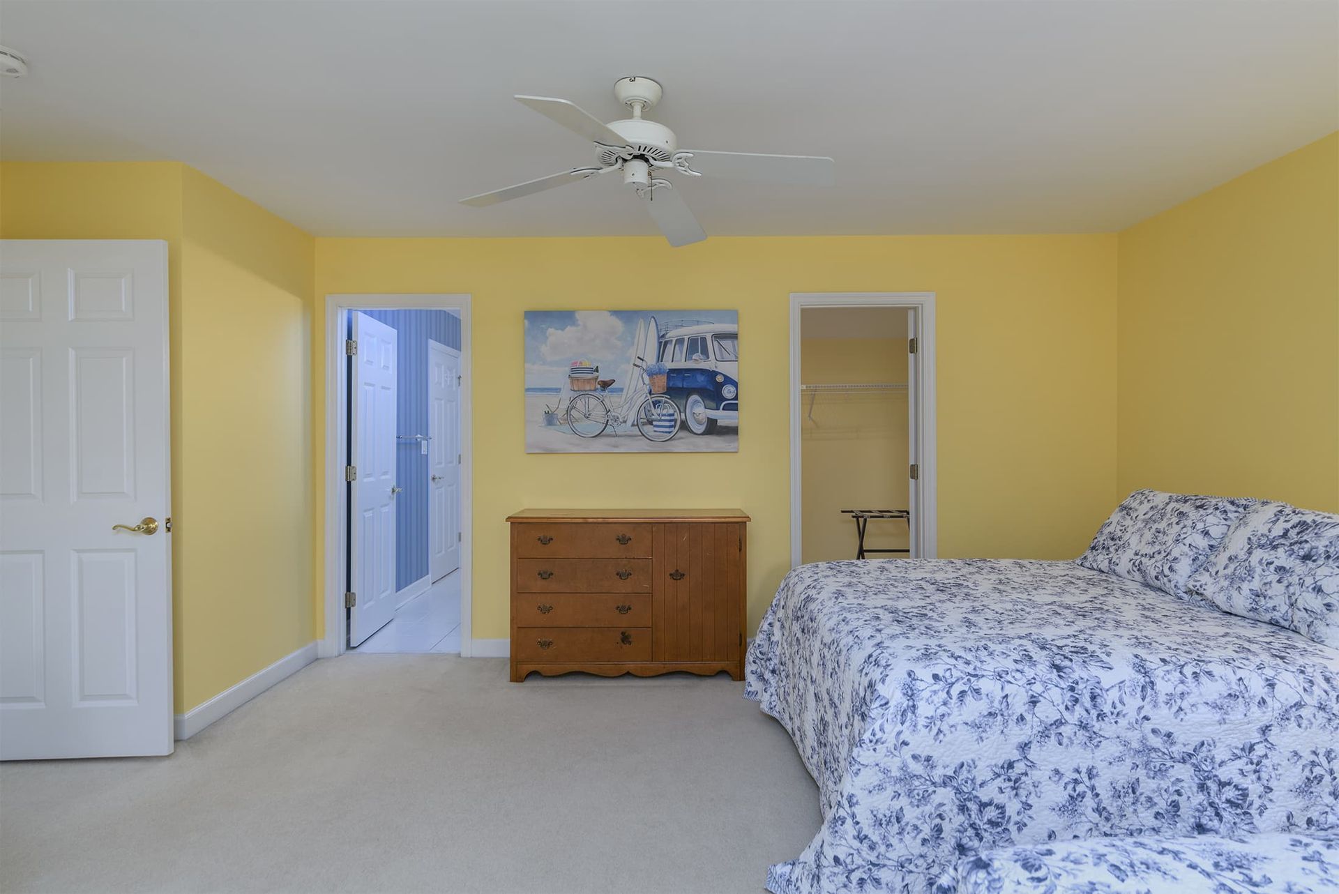 A bedroom with two beds , a dresser , and a ceiling fan.