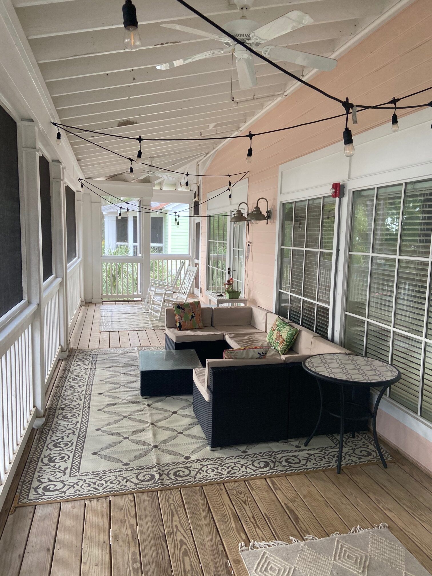 A large porch with a lot of furniture and a ceiling fan.