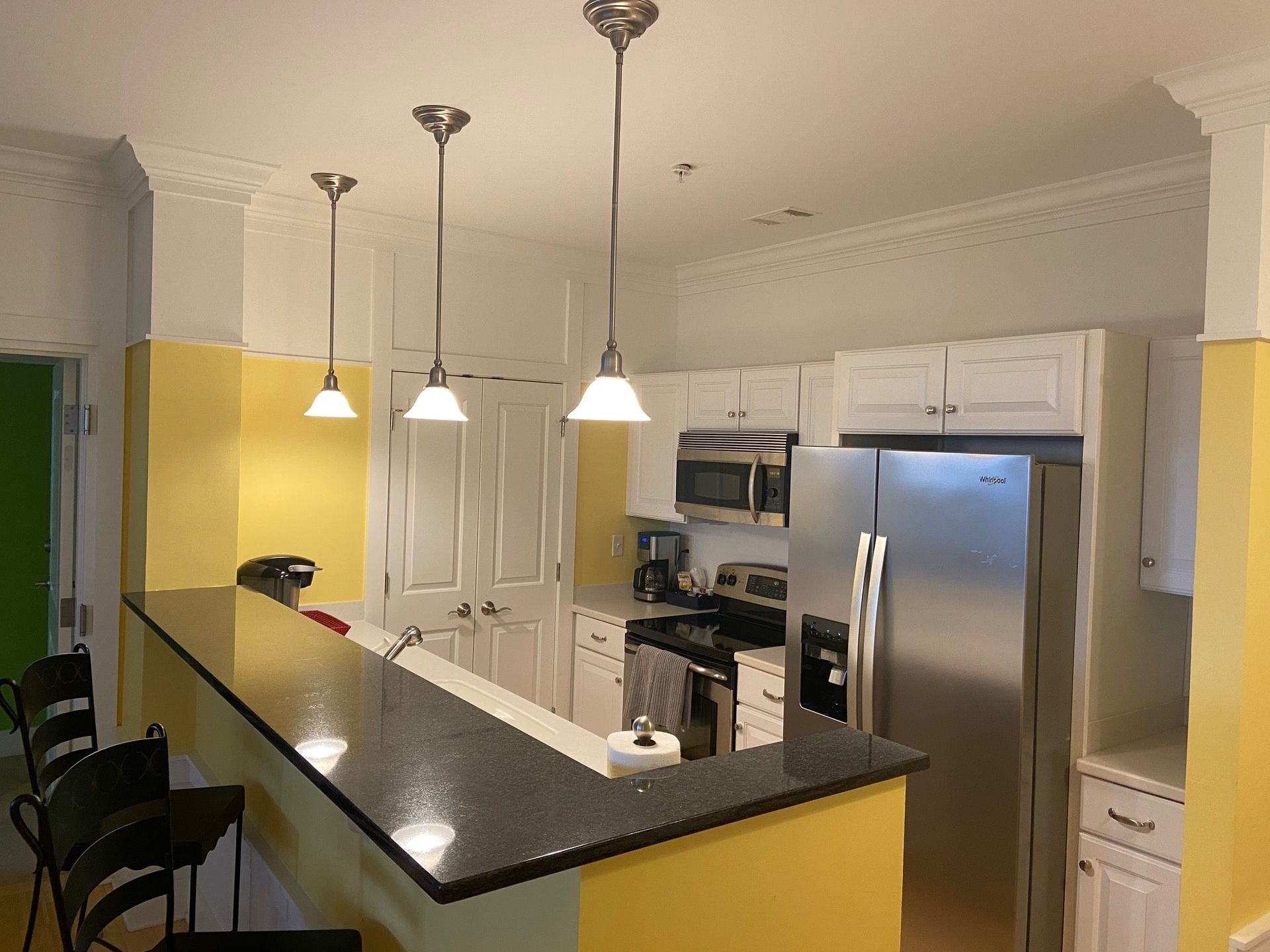 A kitchen with stainless steel appliances and yellow walls