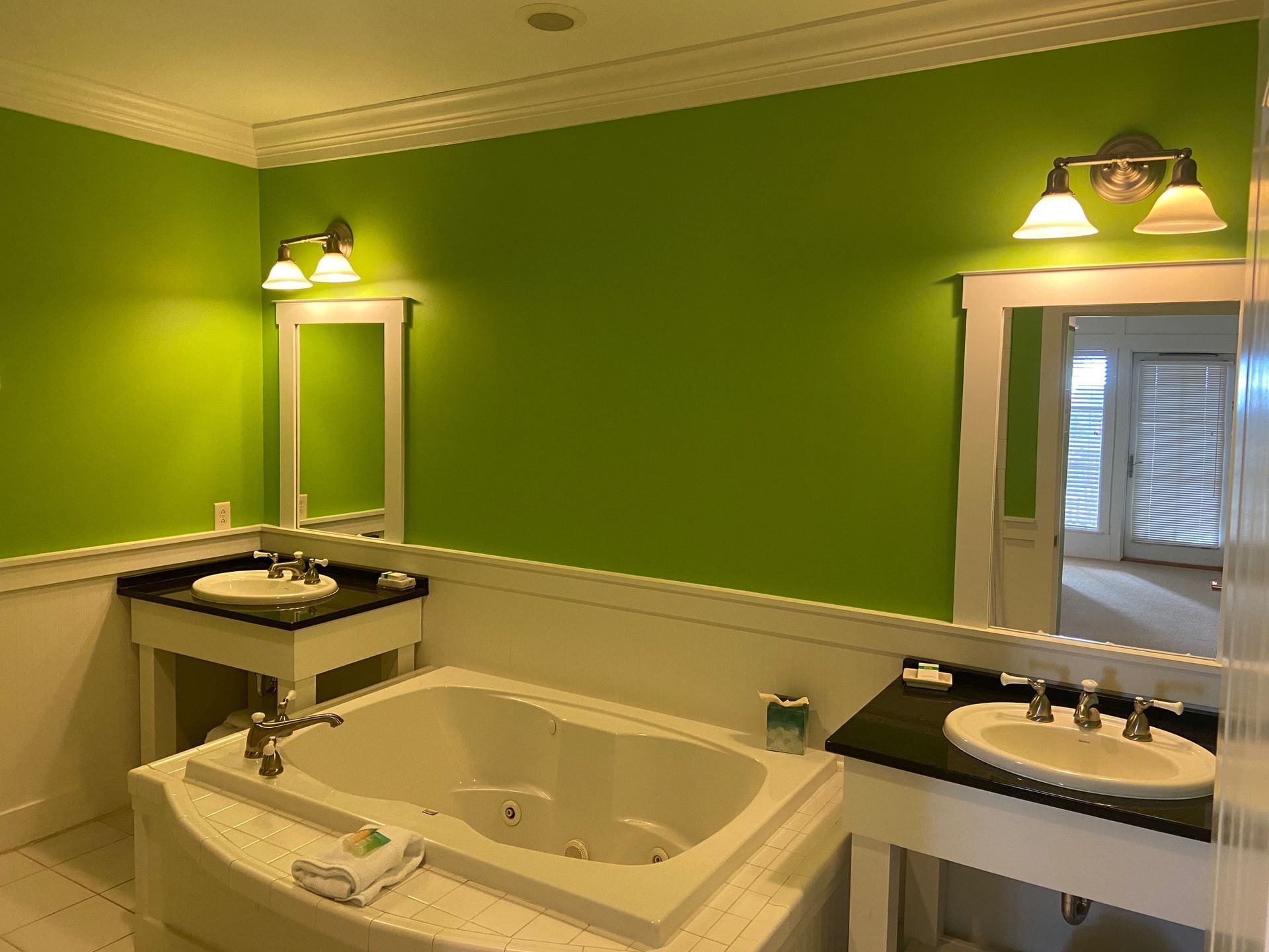 A bathroom with green walls and a jacuzzi tub.