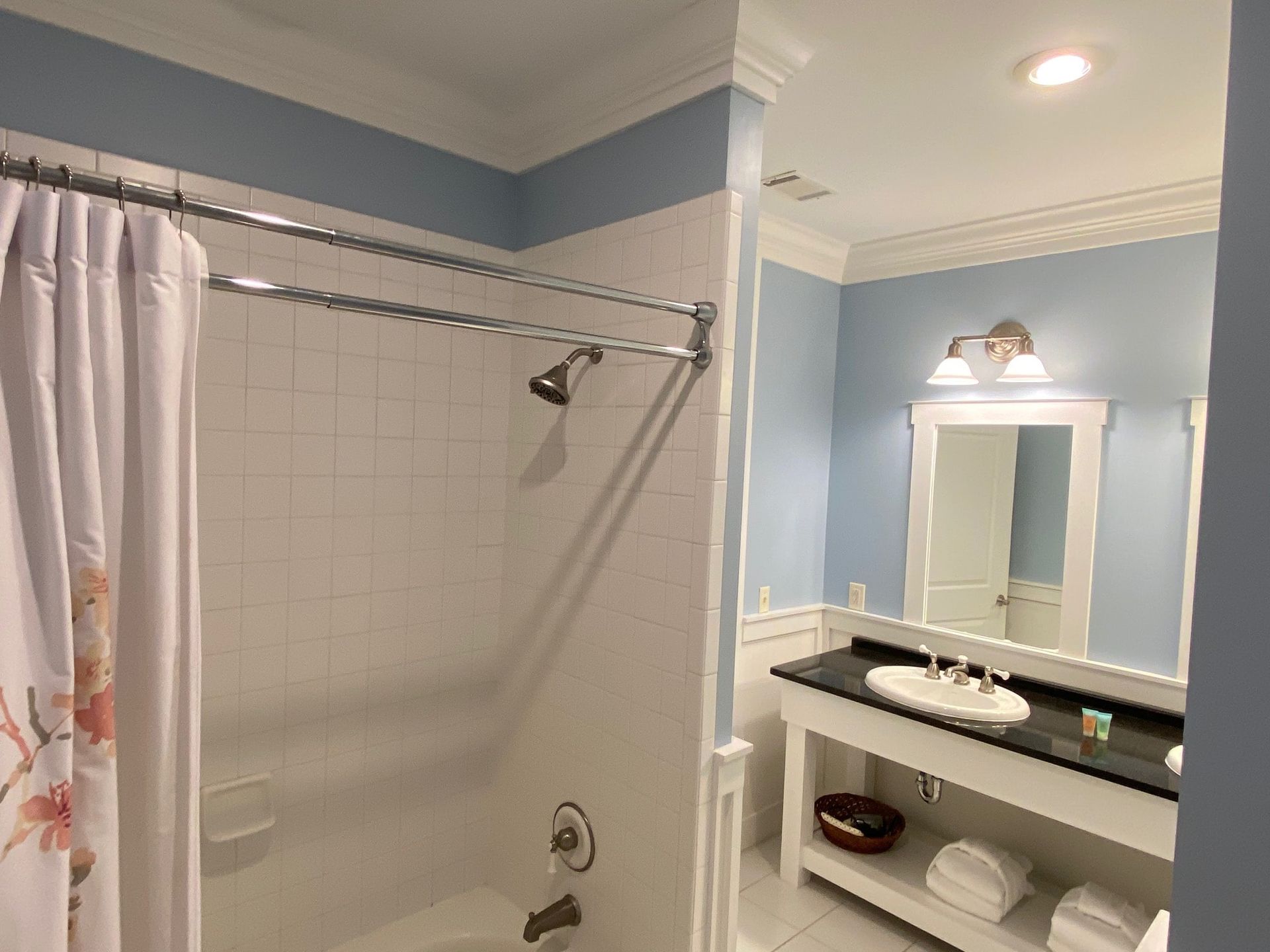 A bathroom with a tub , sink , mirror and shower curtain.