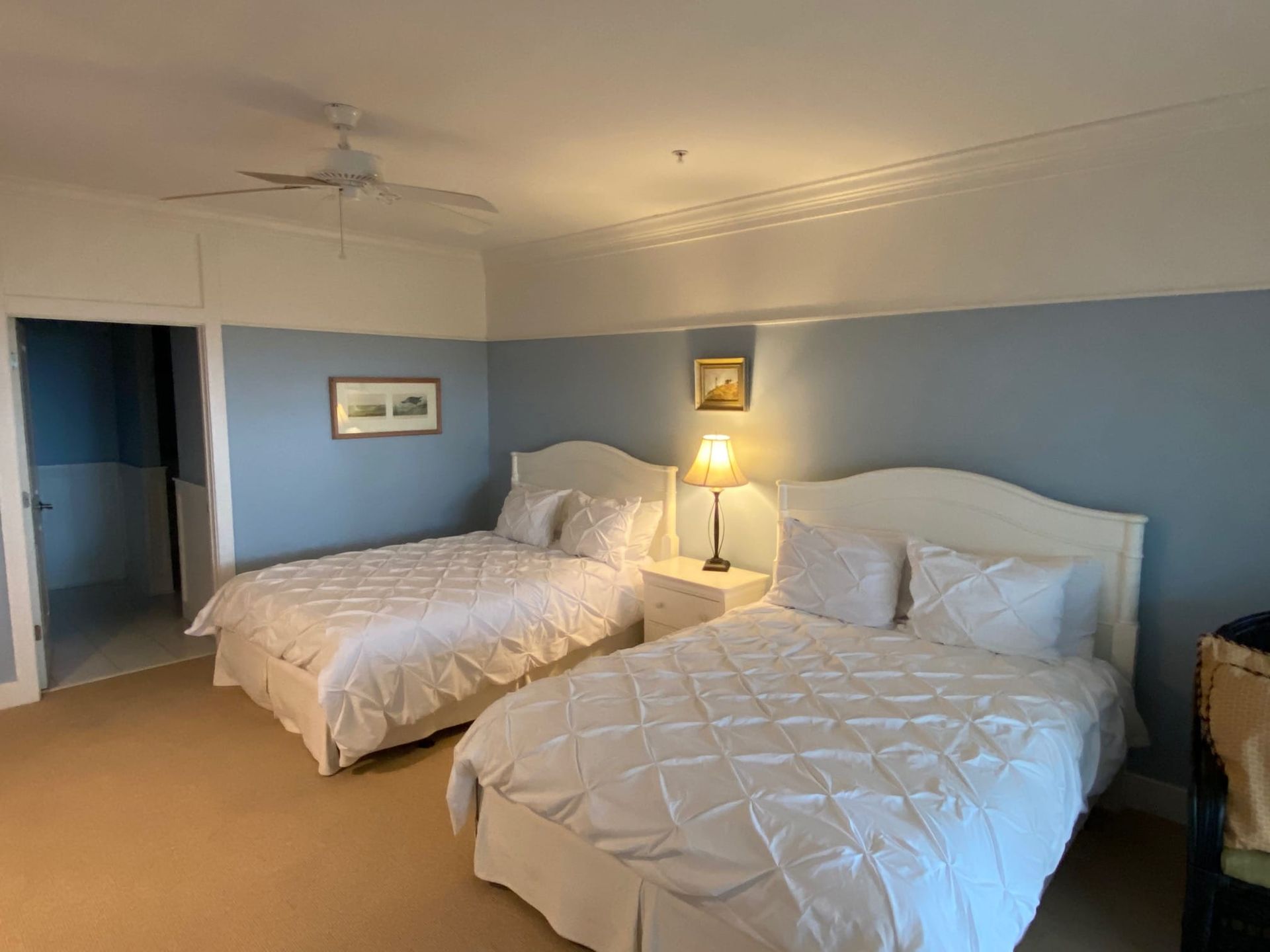 A hotel room with two beds and a ceiling fan.