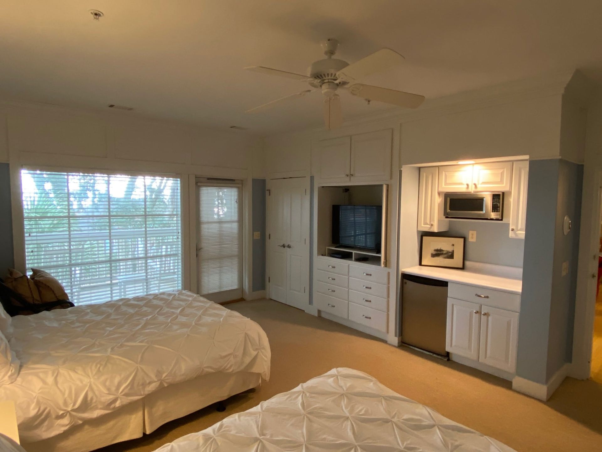 A bedroom with two beds and a ceiling fan