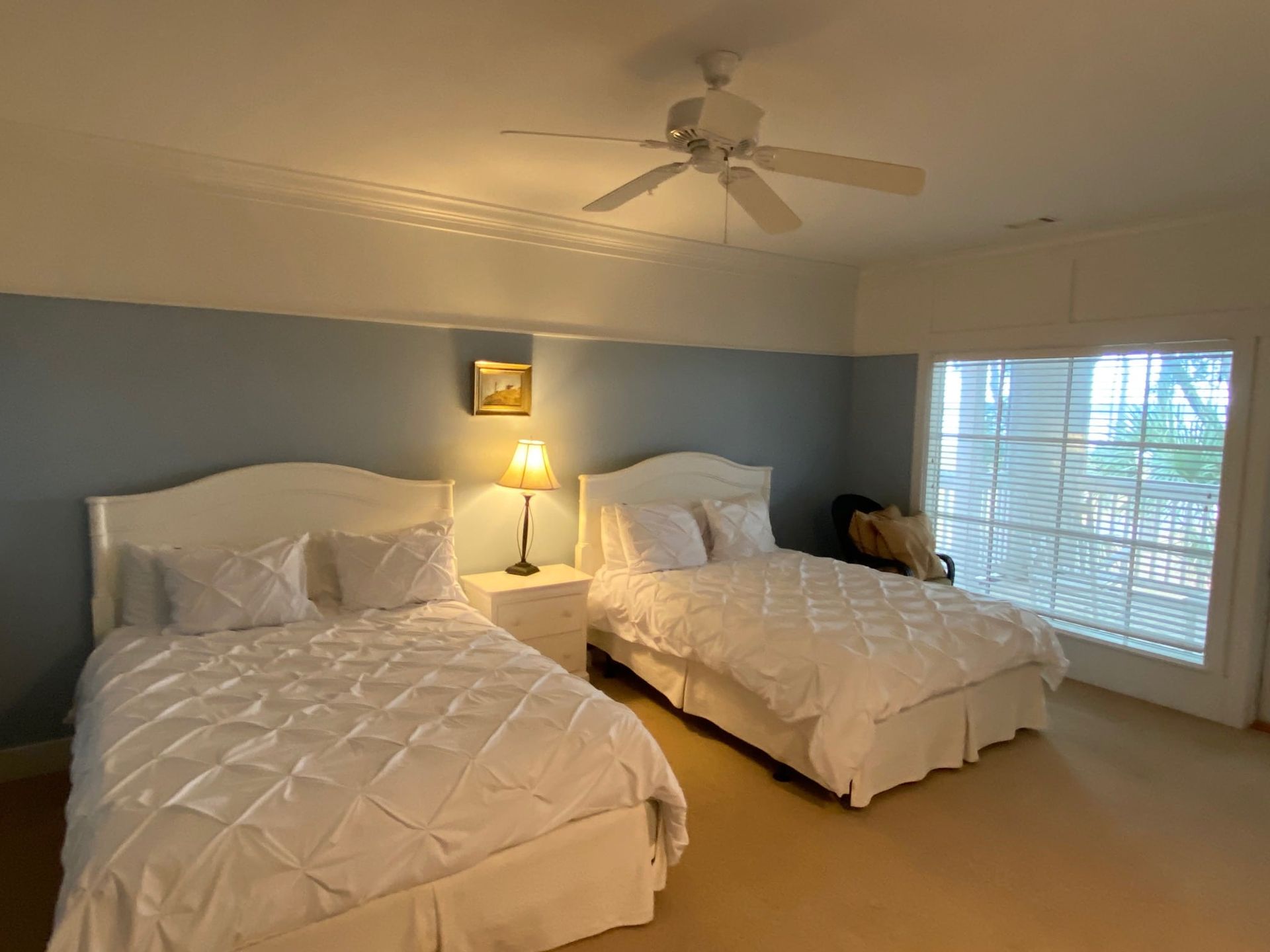 A bedroom with two beds and a ceiling fan.