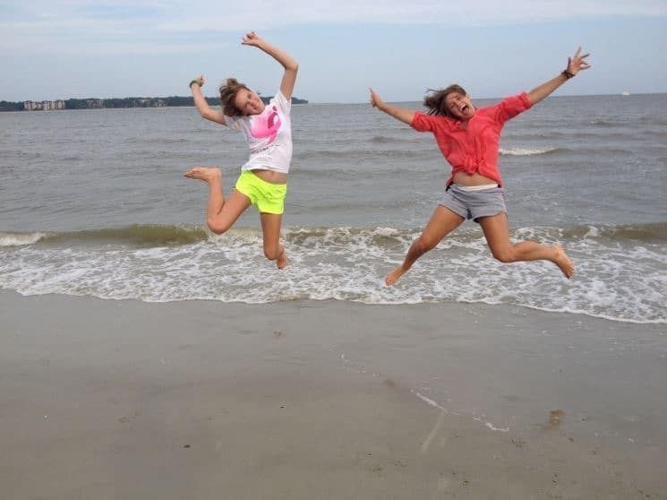 Two girls are jumping in the air on the beach