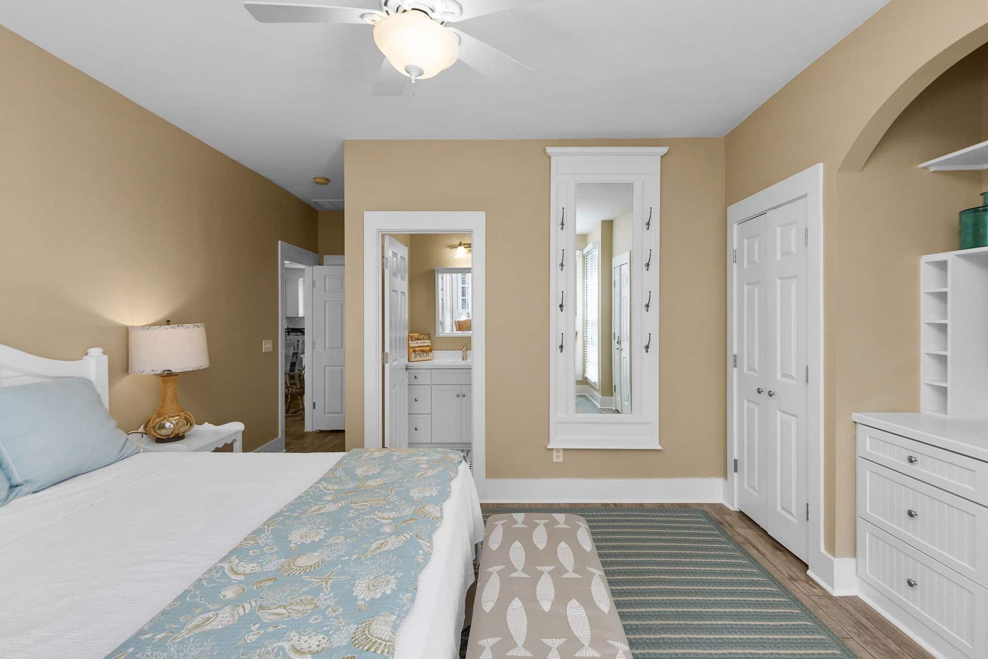 A bedroom with a bed , dresser , ceiling fan and mirror.