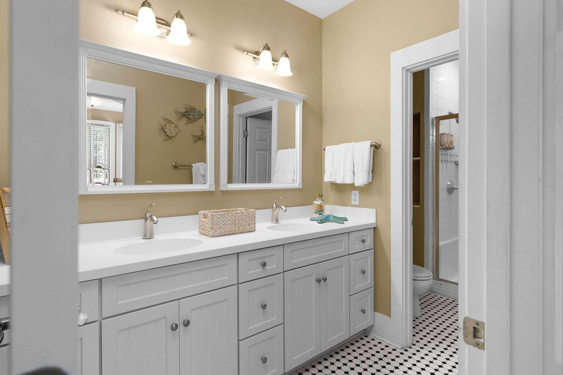 A bathroom with two sinks , two mirrors , and a tiled floor.