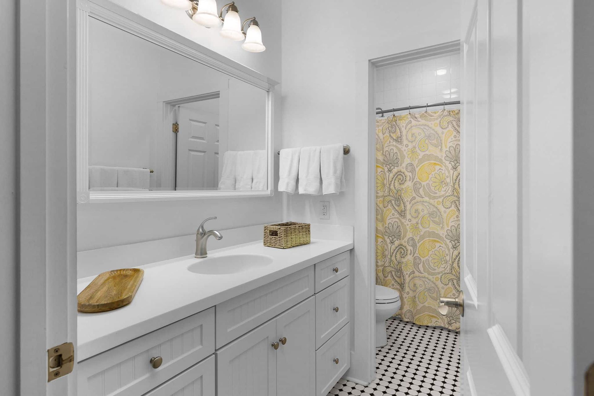 A bathroom with a sink , mirror and shower curtain.