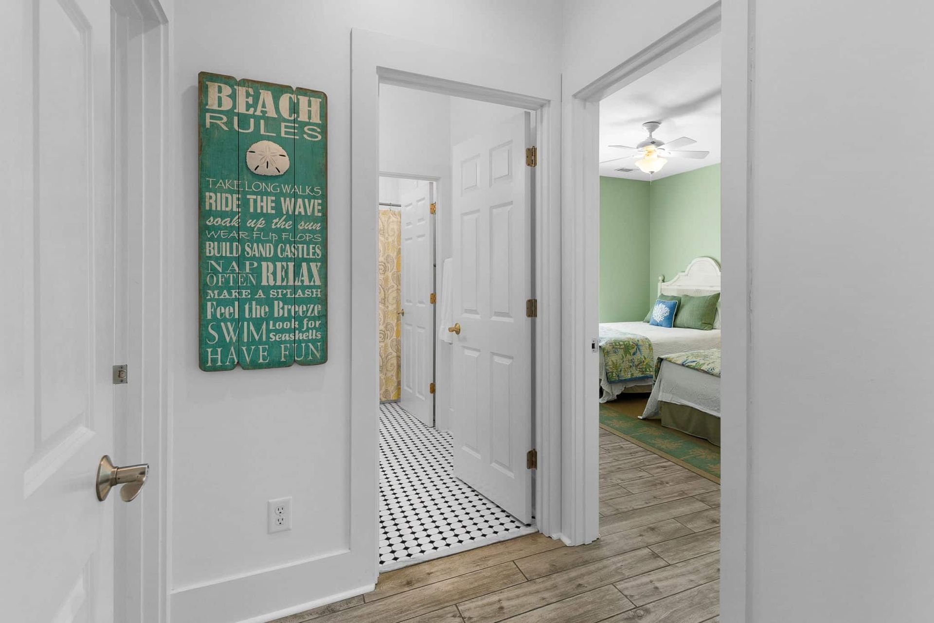 A hallway in a house with a sign on the wall that says `` beach rules ''.