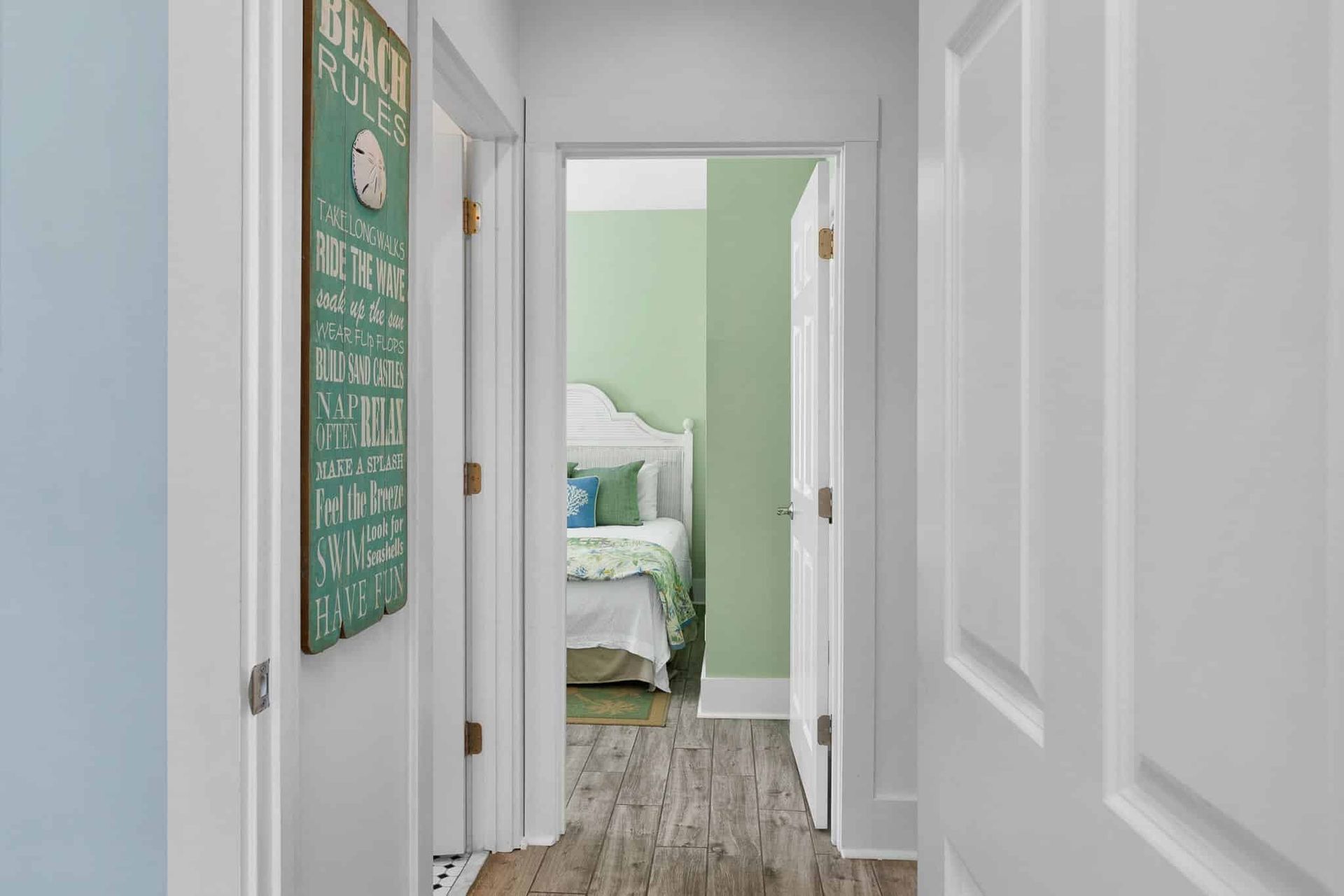A hallway leading to a bedroom with a bed and a sign on the wall.