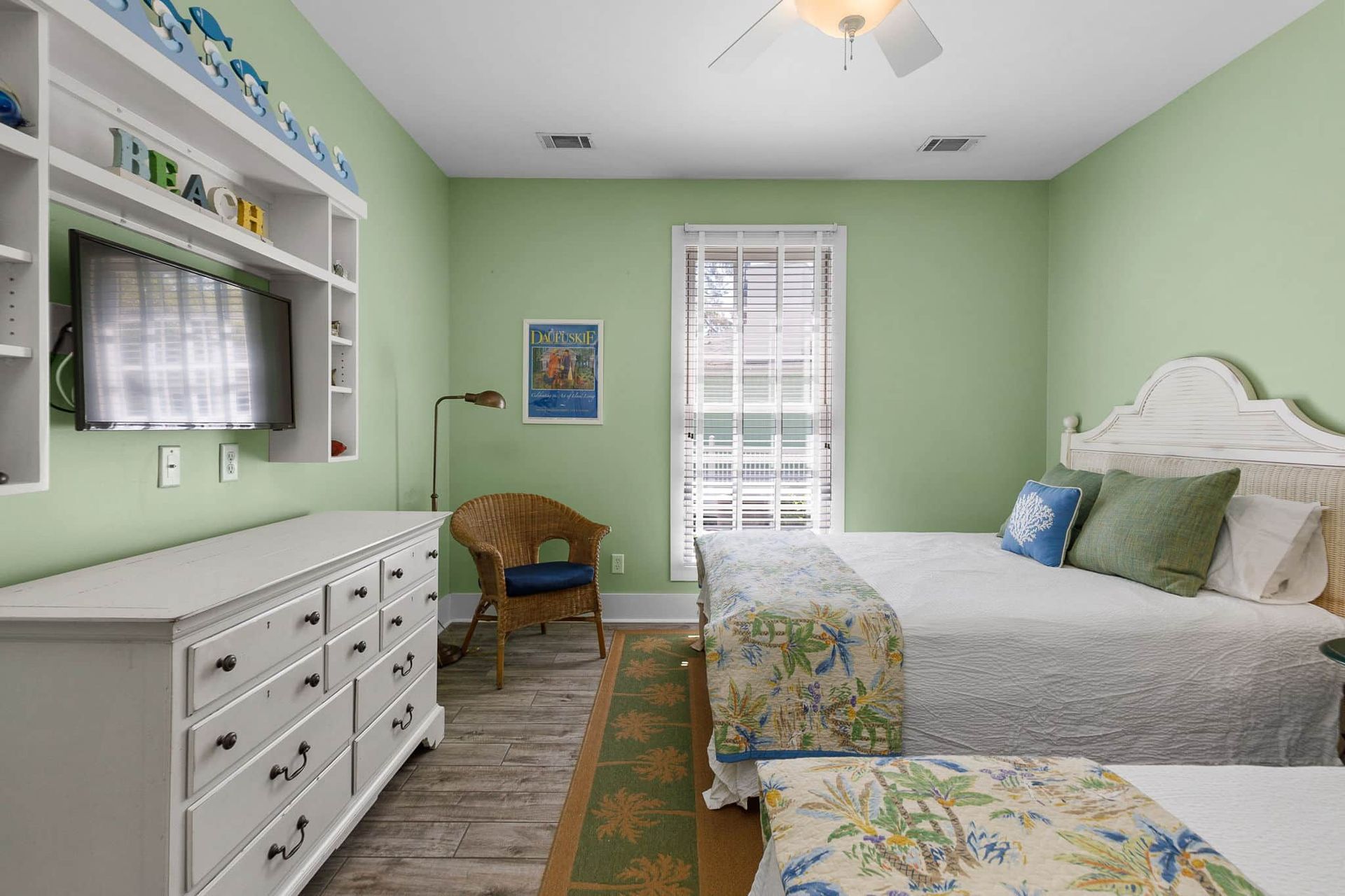 A bedroom with two beds , a dresser , a chair and a television.