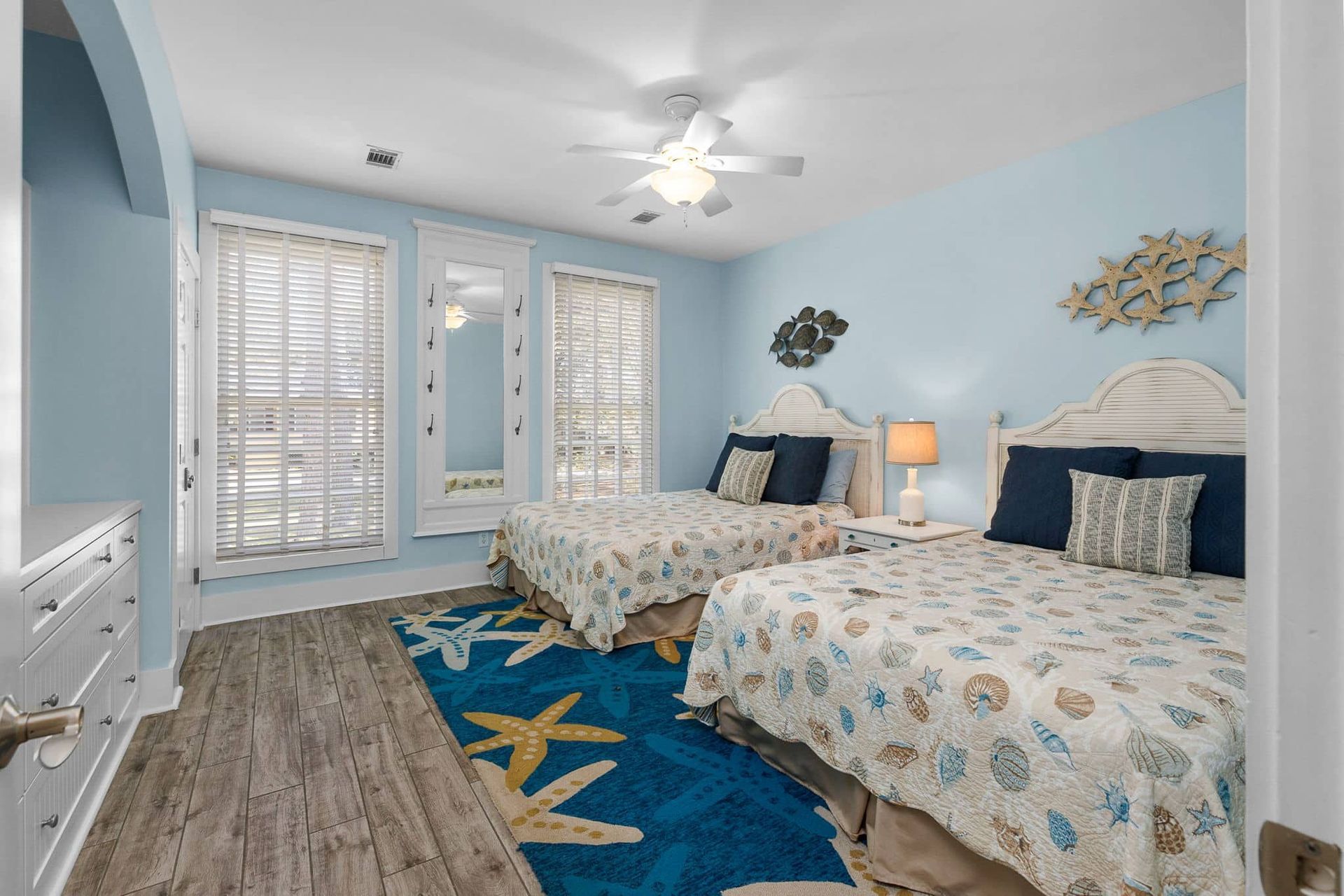 A bedroom with two beds , a rug and a ceiling fan.
