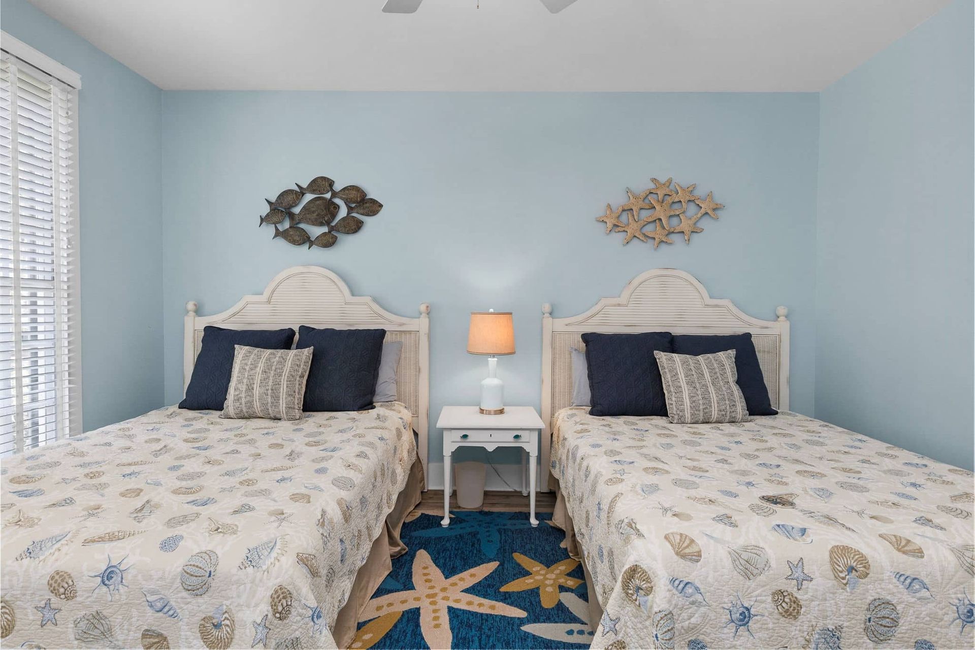 A bedroom with two beds , a nightstand and a rug.