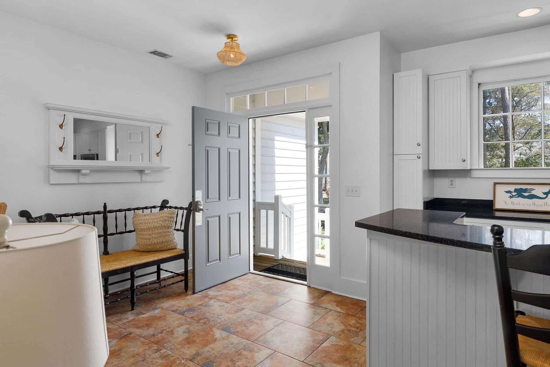 A living room with a bench and a door leading to a kitchen.