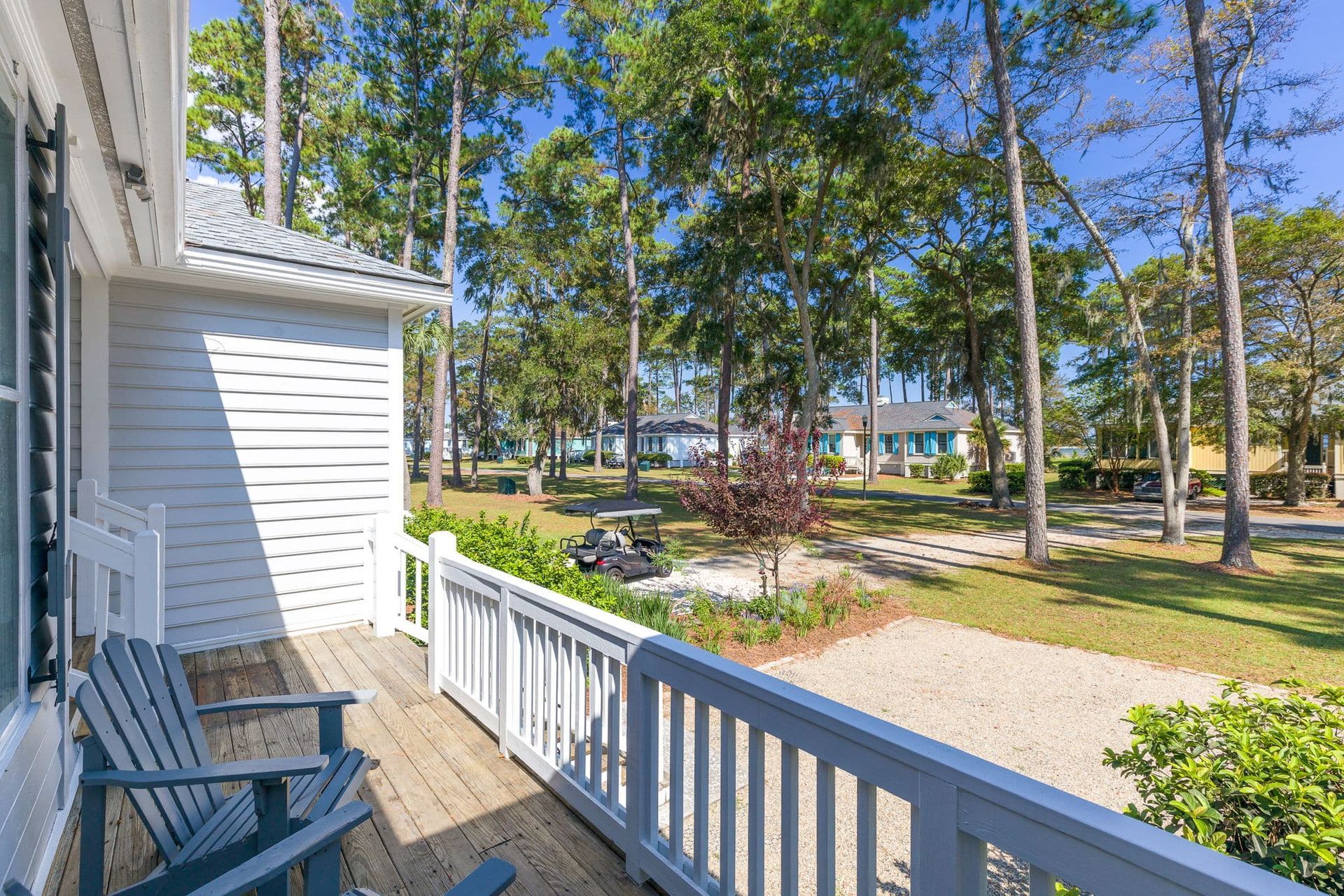 There are two chairs on the deck of a house.