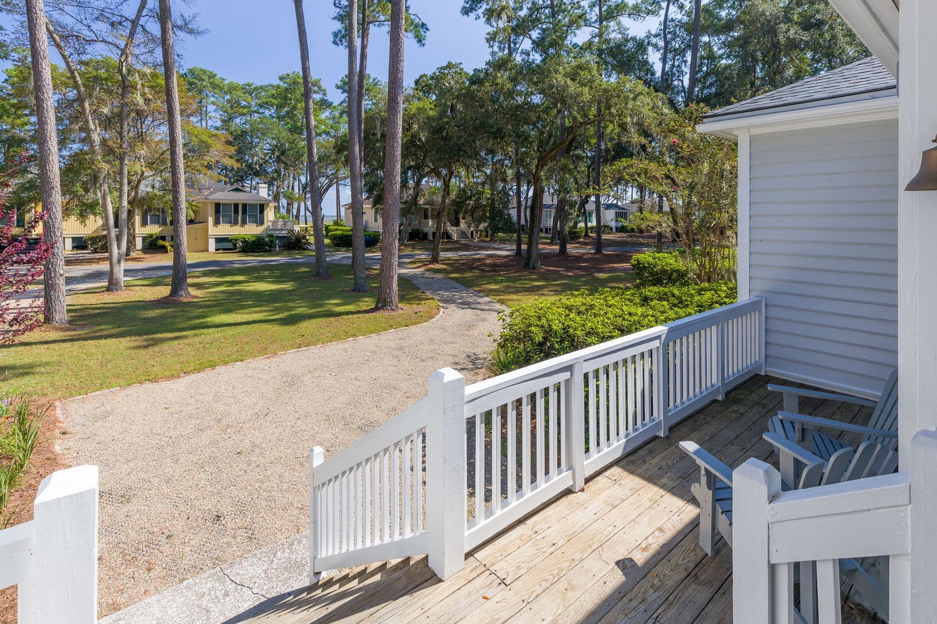 A white house with a wooden deck and a white fence surrounding it.