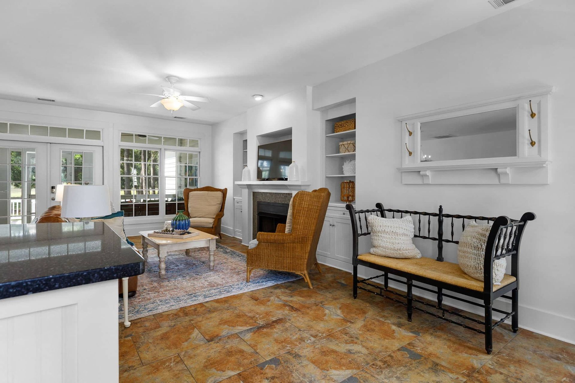 A living room with a bench , chairs , coffee table and fireplace.
