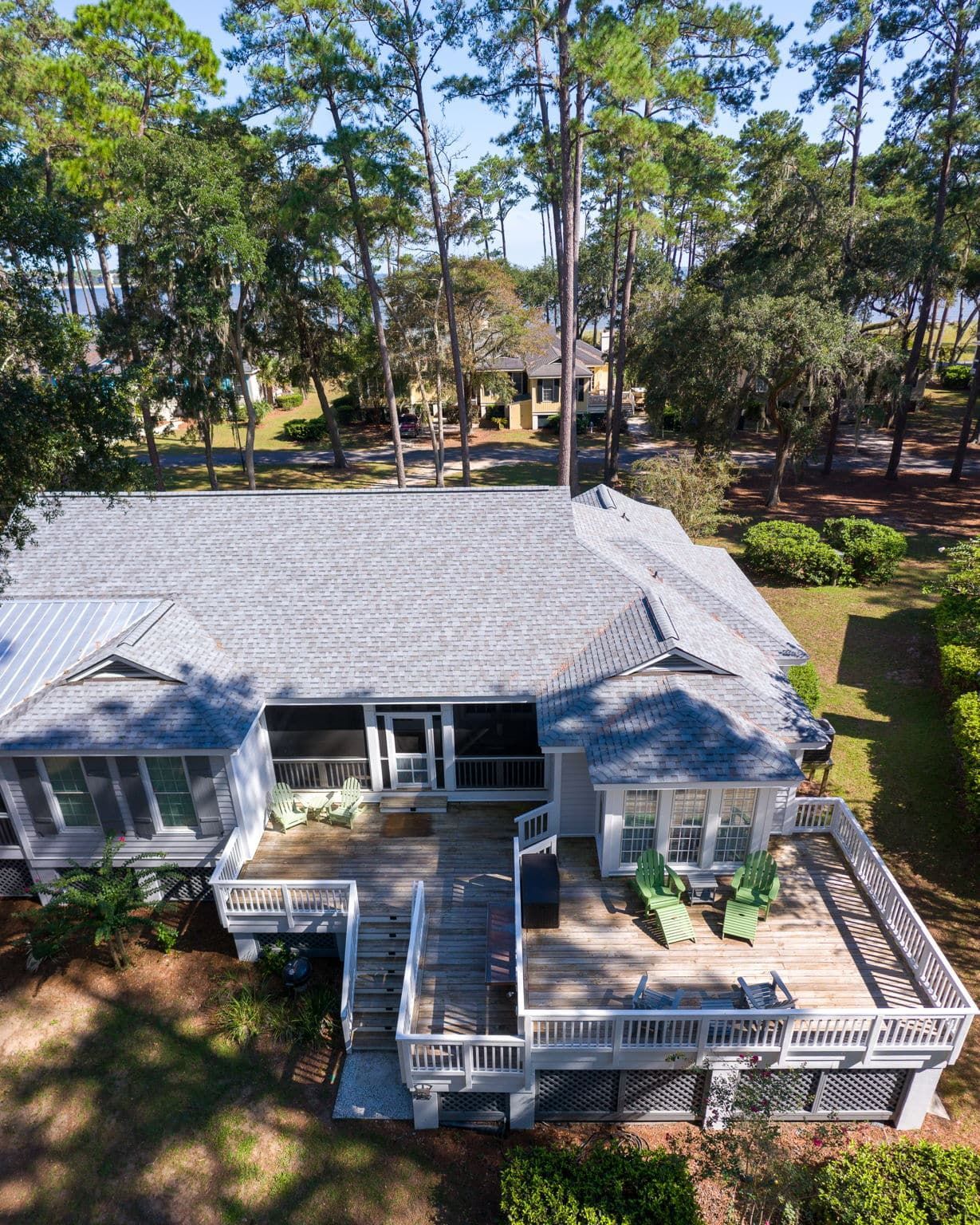 An aerial view of a house with a large deck surrounded by trees.
