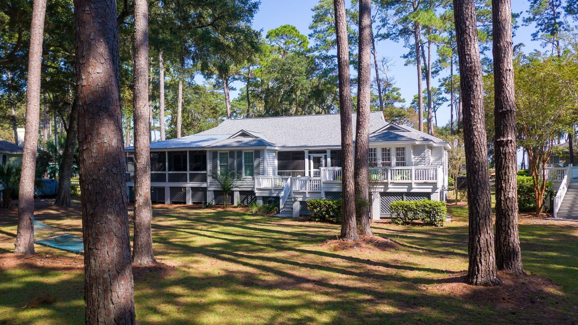 A house with a screened in porch is surrounded by trees.