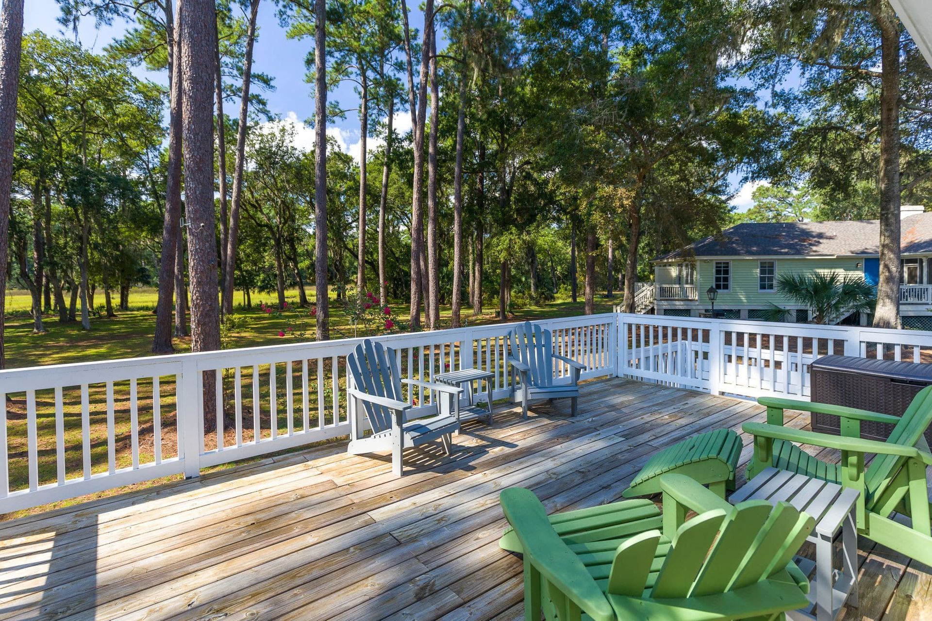 A wooden deck with green chairs and a white railing