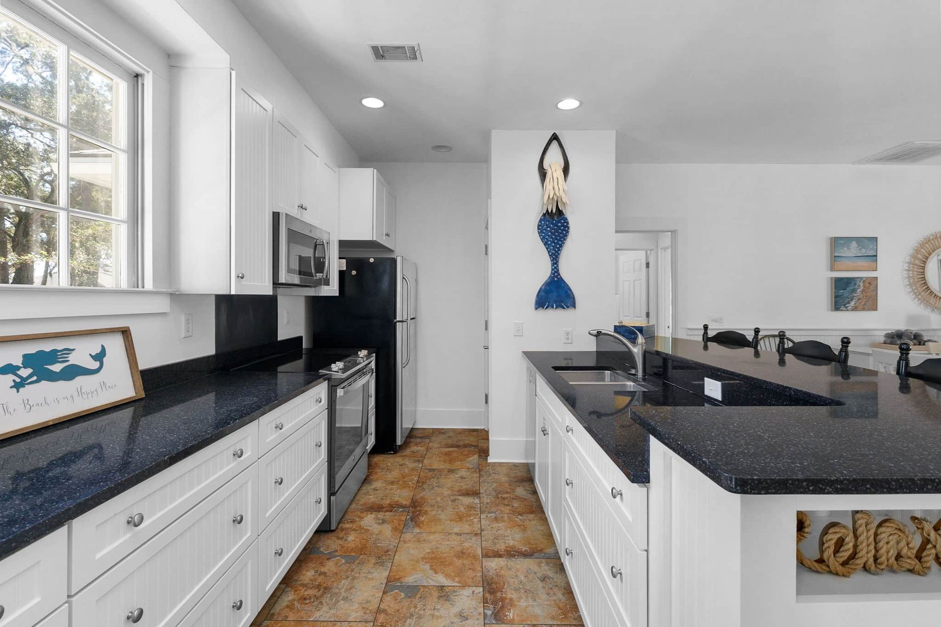 A kitchen with black granite counter tops and white cabinets.