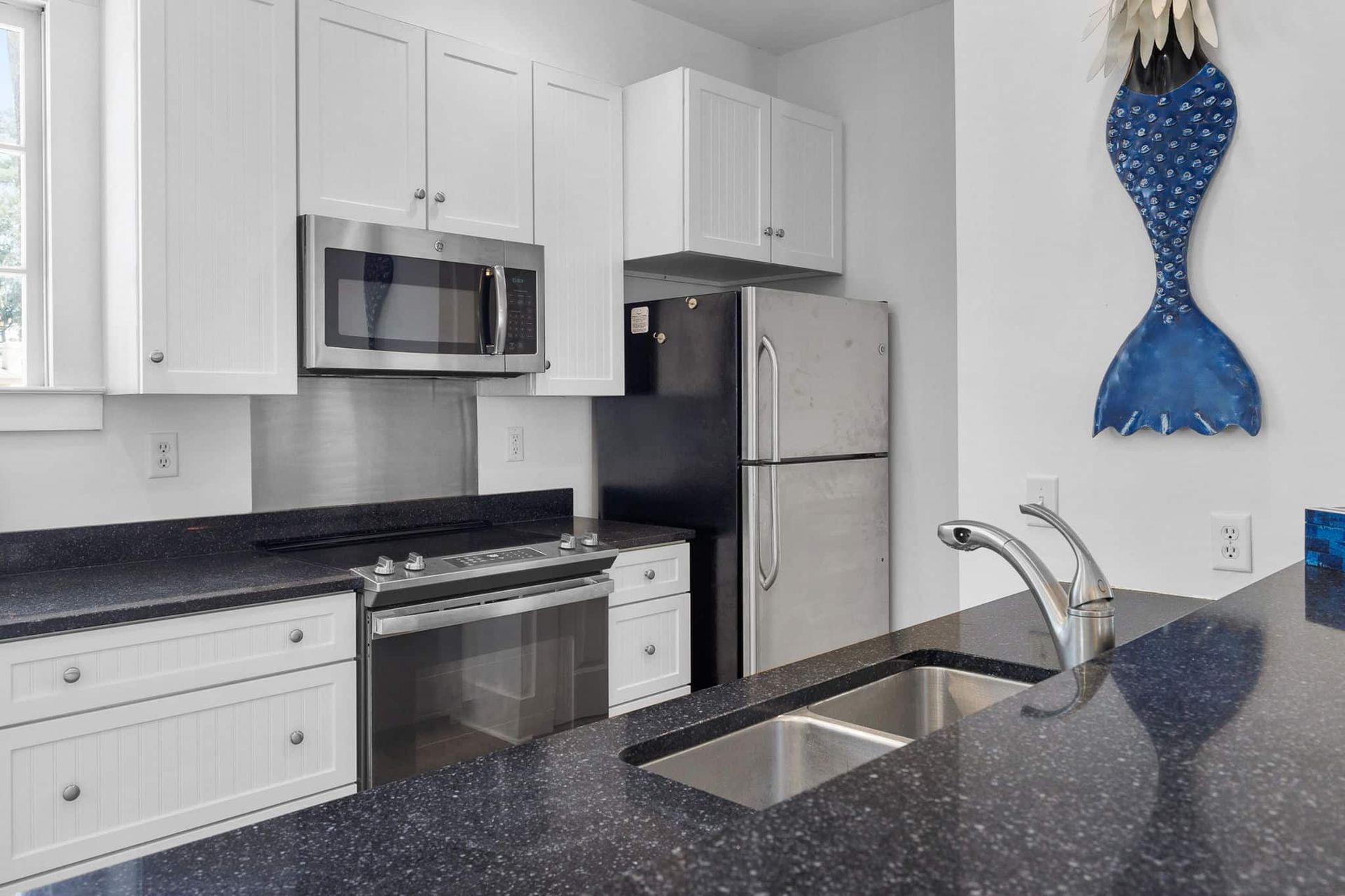 A kitchen with stainless steel appliances and a mermaid tail on the wall