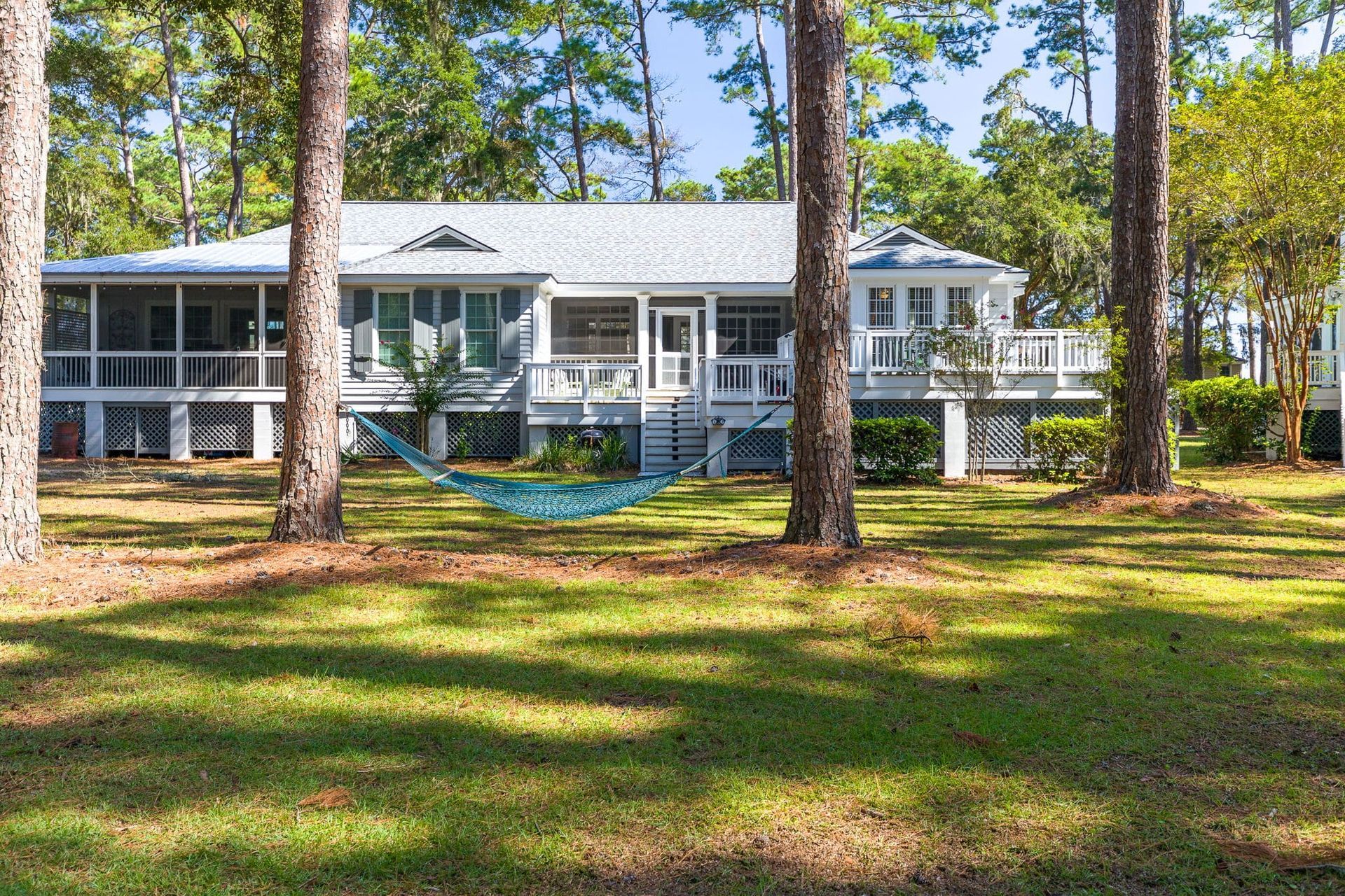 A house with a hammock in front of it surrounded by trees.