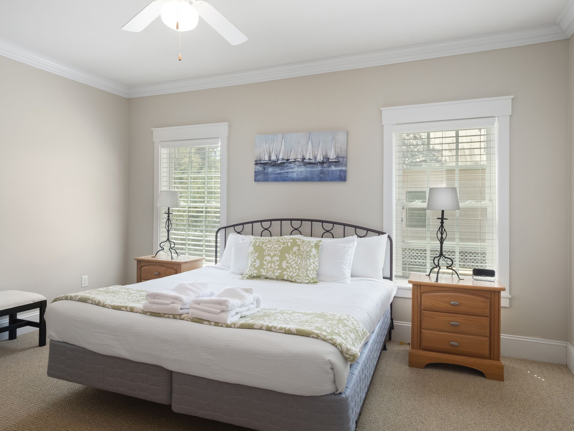 A bedroom with a king size bed , two nightstands and a ceiling fan.