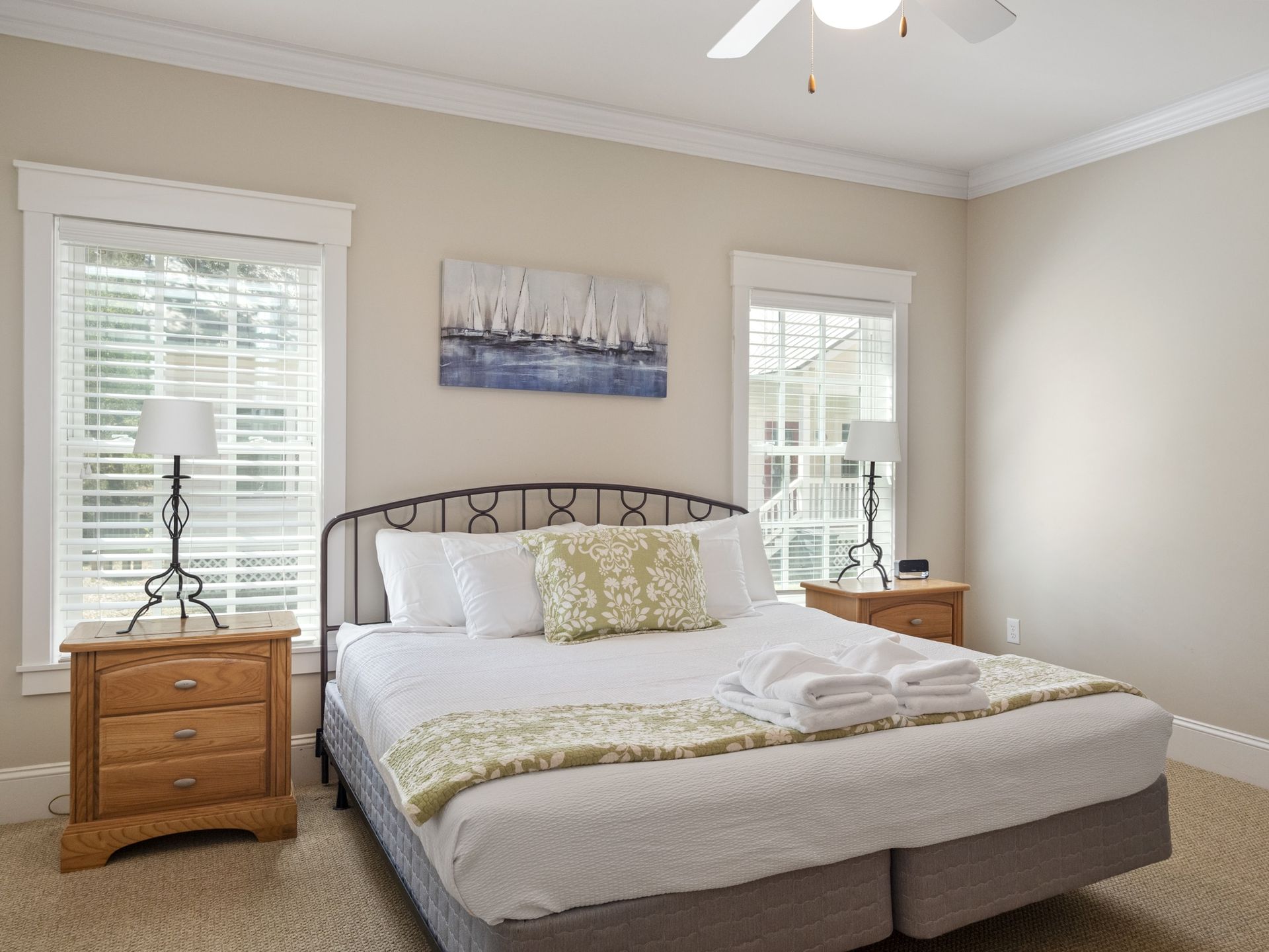 A bedroom with a king size bed , two nightstands and a ceiling fan.