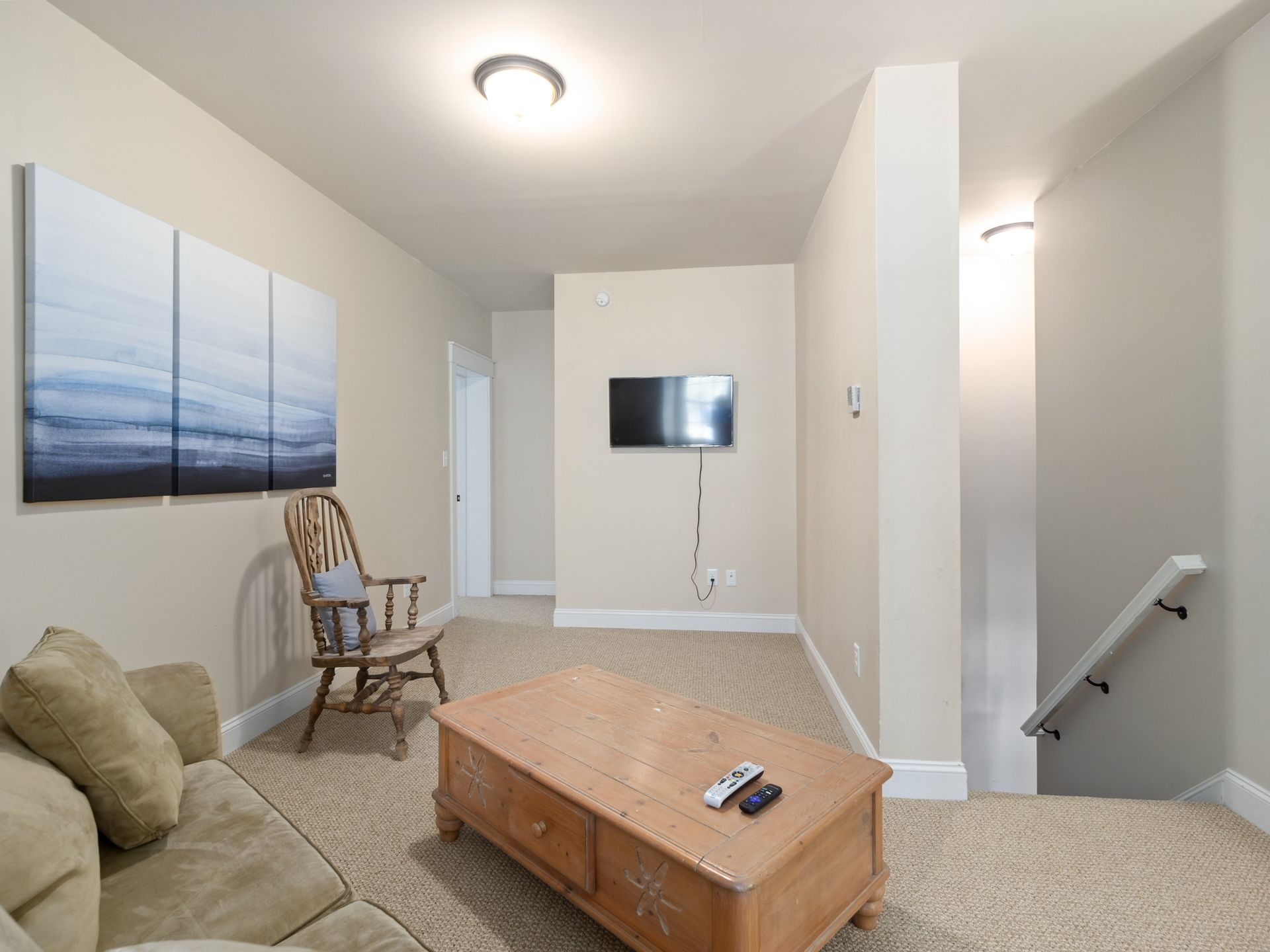 A living room with a couch , chair , coffee table and television.