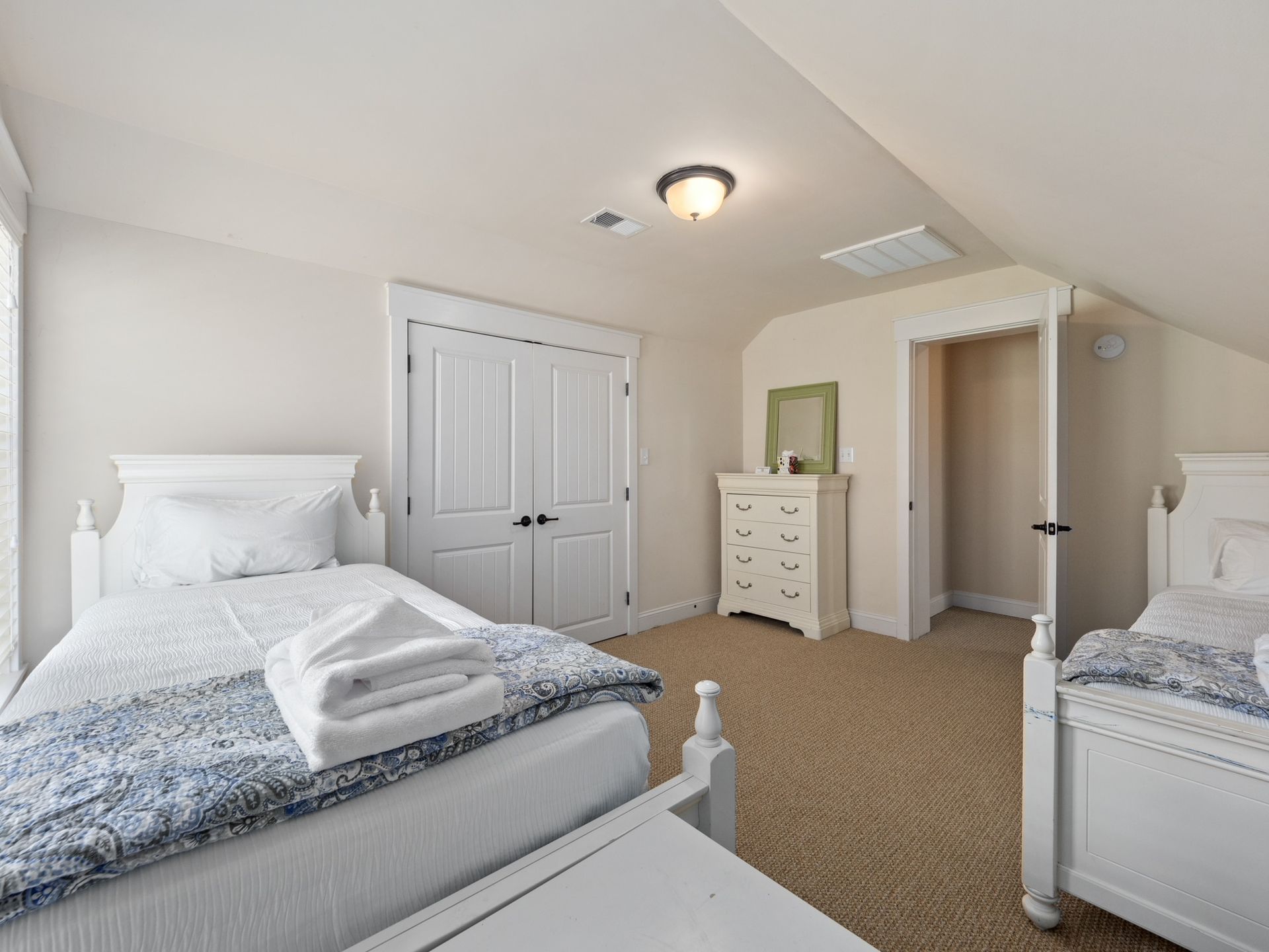 A bedroom with two beds and a dresser.