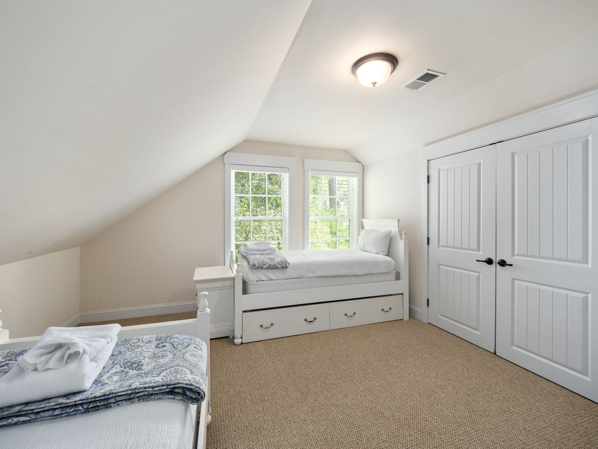 A bedroom with two beds and a window.