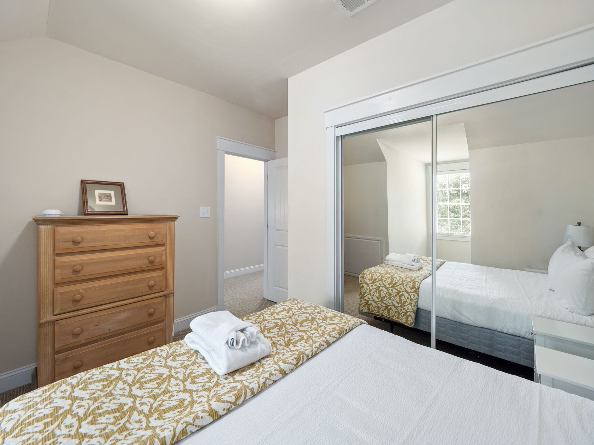 A bedroom with a bed , dresser , nightstand and sliding glass doors.