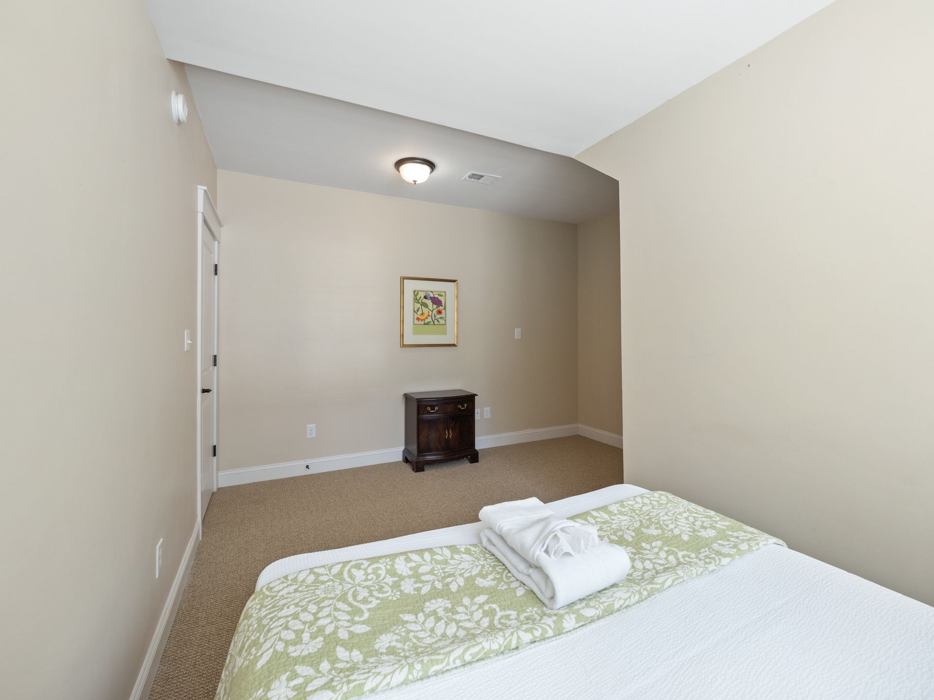 A bedroom with a bed , nightstand , and picture on the wall.